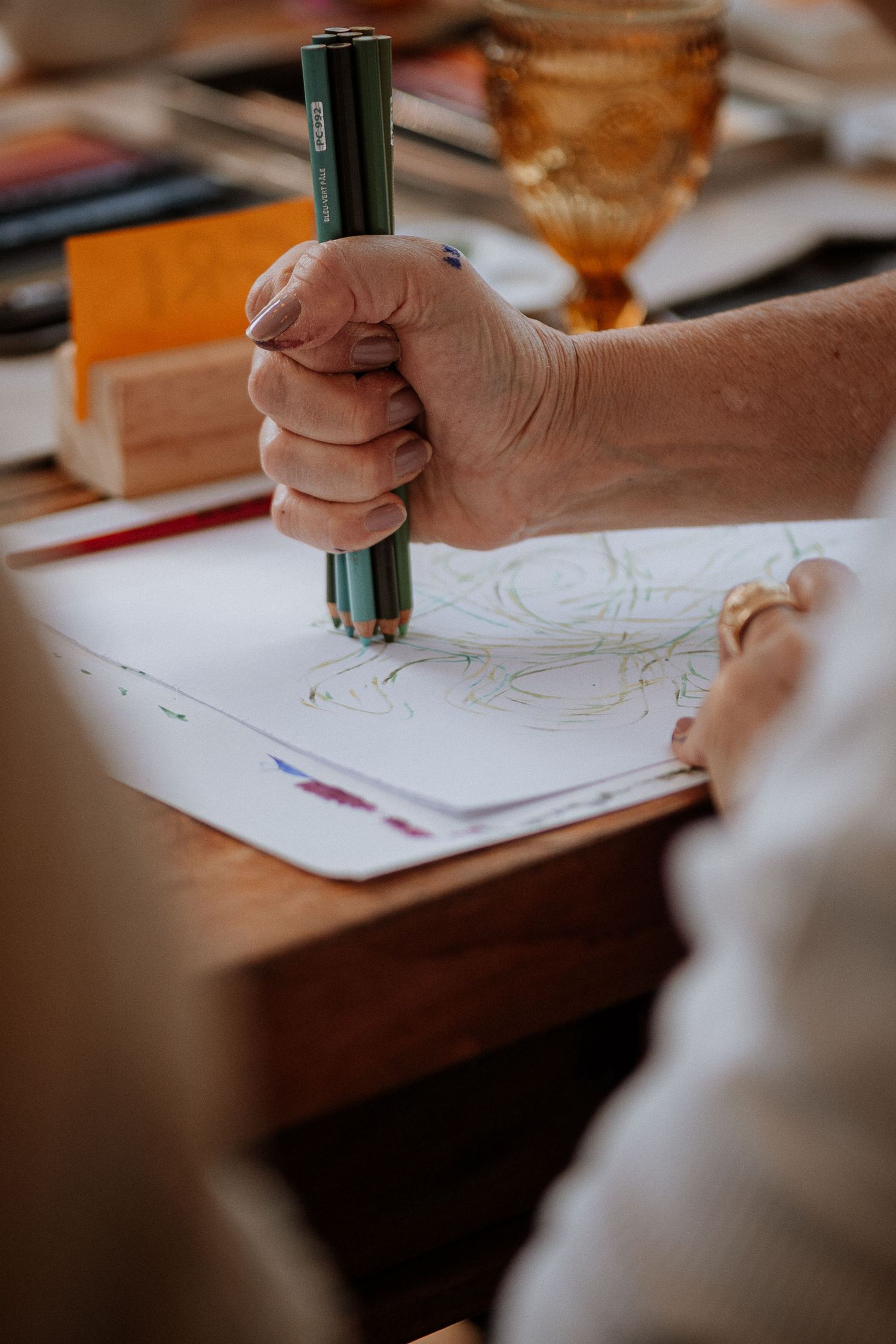 Close-up shot of hands drawing or writing with a green pen on white paper during a workshop session.