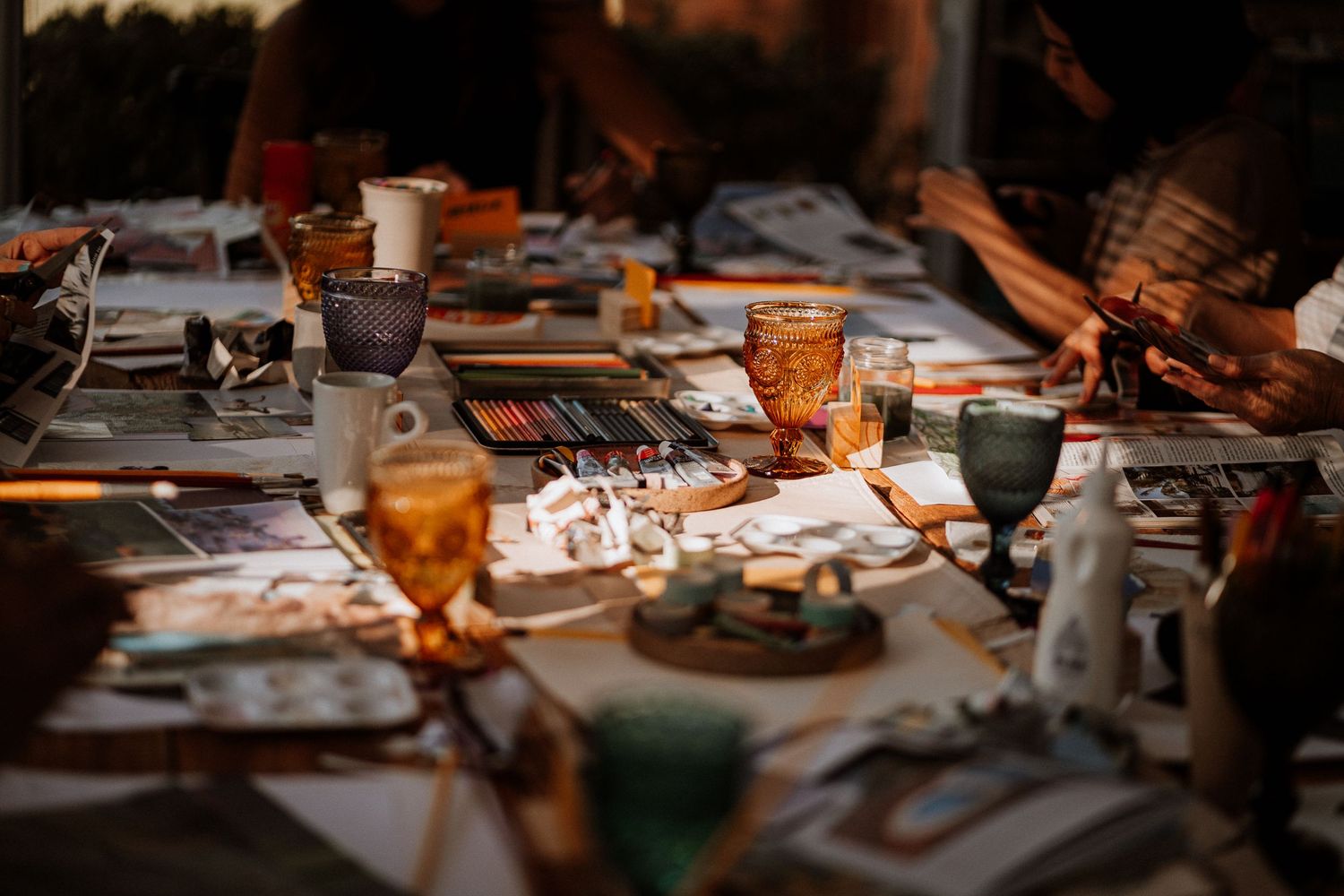 Creative workshop materials spread across a dark wooden table with warm lighting.