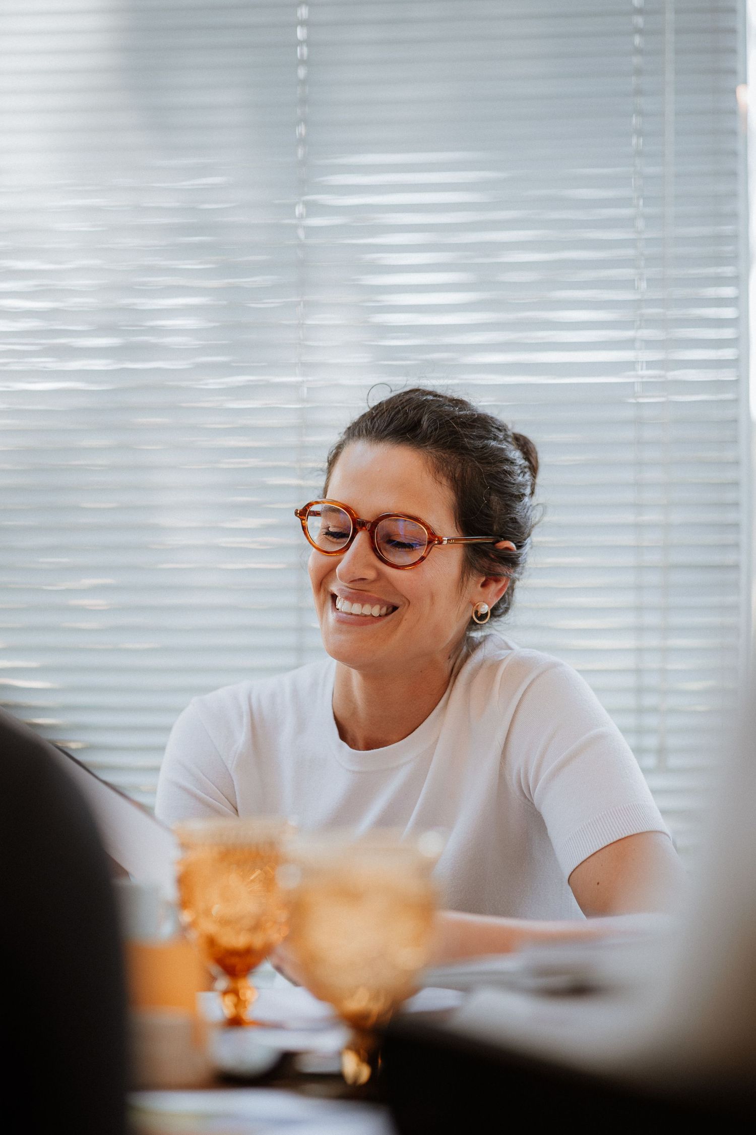 Workshop participant in white shirt seated by window blinds during a creative session.