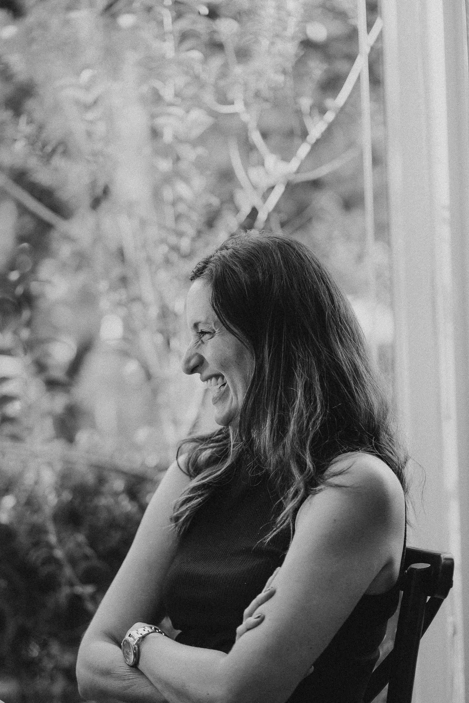 Black and white portrait of someone laughing while seated outdoors.