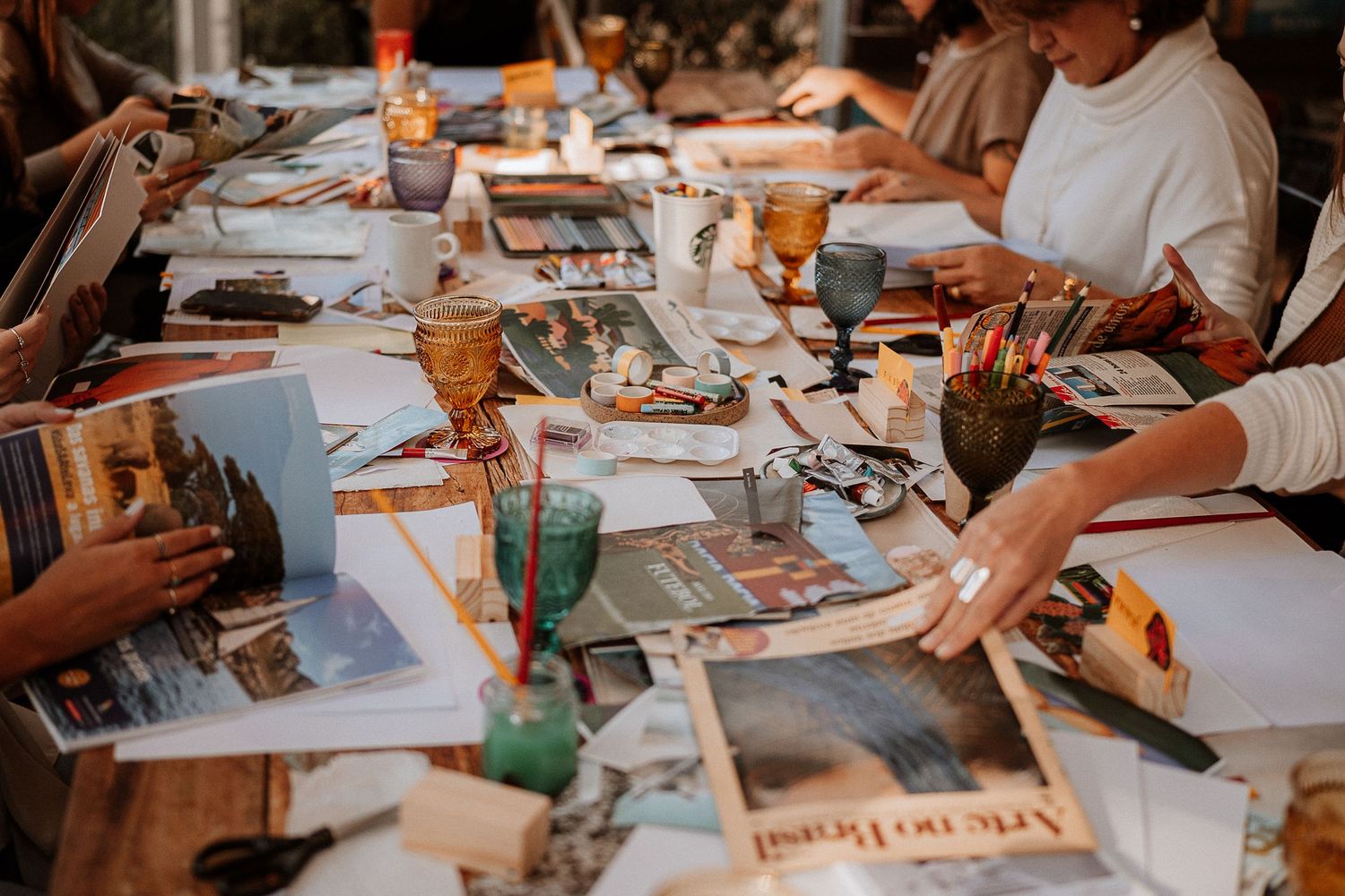 Overhead view of creative materials and supplies spread across workshop tables.