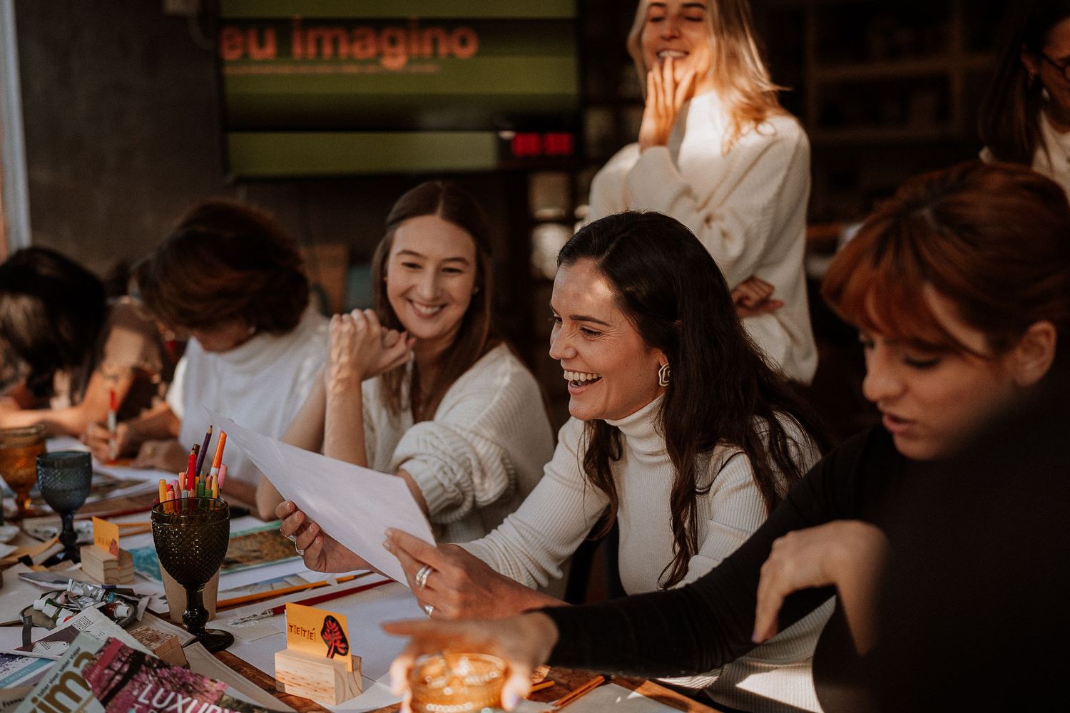 Group gathered around a table with papers and candles in a dimly lit setting.