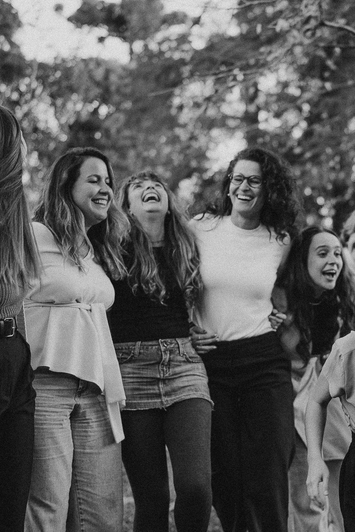 Black and white photo of friends laughing together outdoors.
