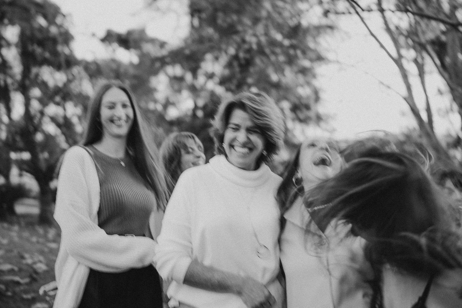 Black and white photo capturing genuine laughter and friendship in an outdoor setting.