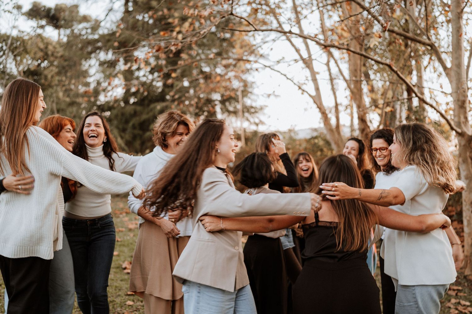 Friends embracing in a group hug outdoors during golden hour with trees in the background.