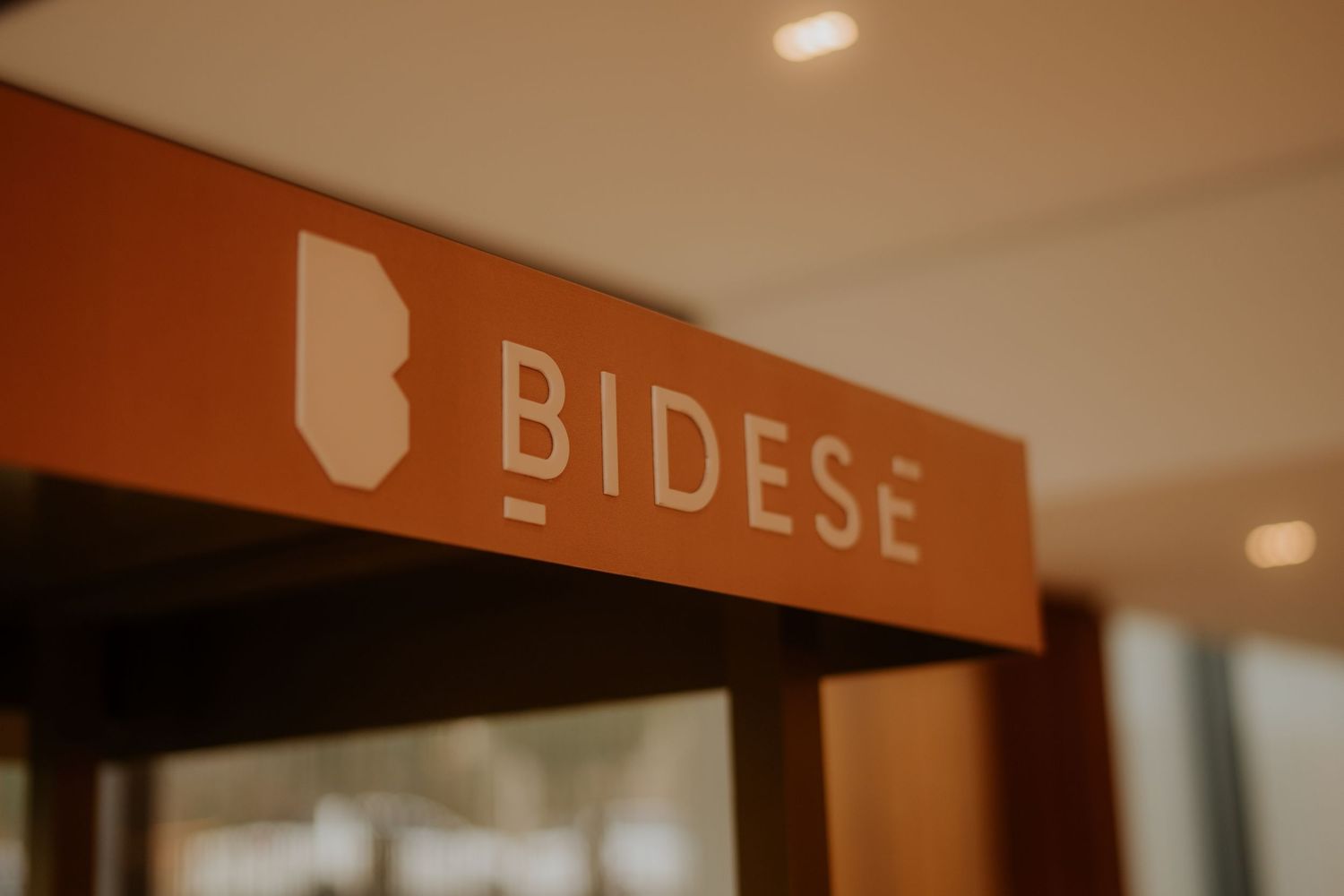 Close-up of Bidese signage in terracotta color mounted on an office wall.