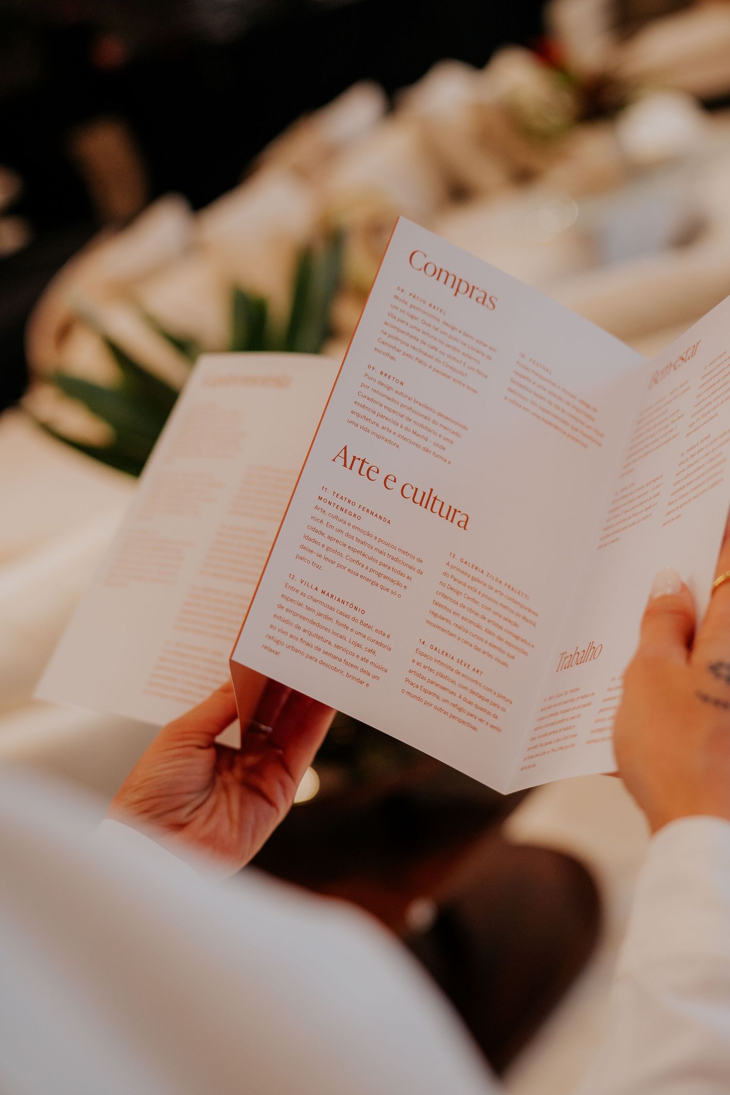 Open book showing Portuguese text sections titled 'Grupos' and 'Arte e cultura' in warm lighting.