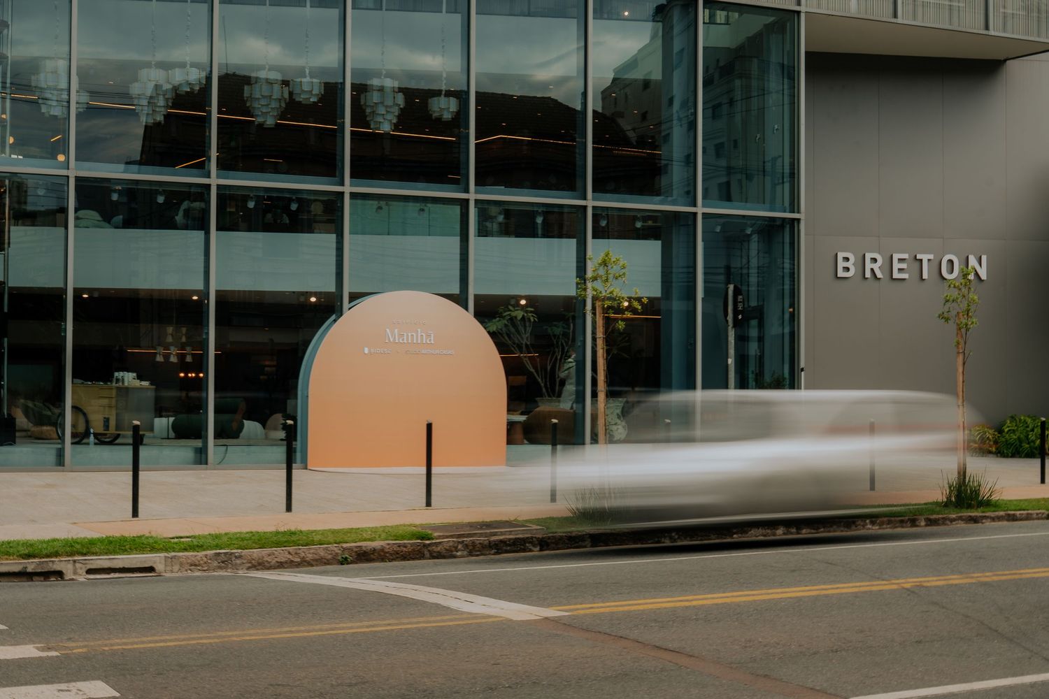 Modern glass building facade with geometric peach-colored arch and motion blur.