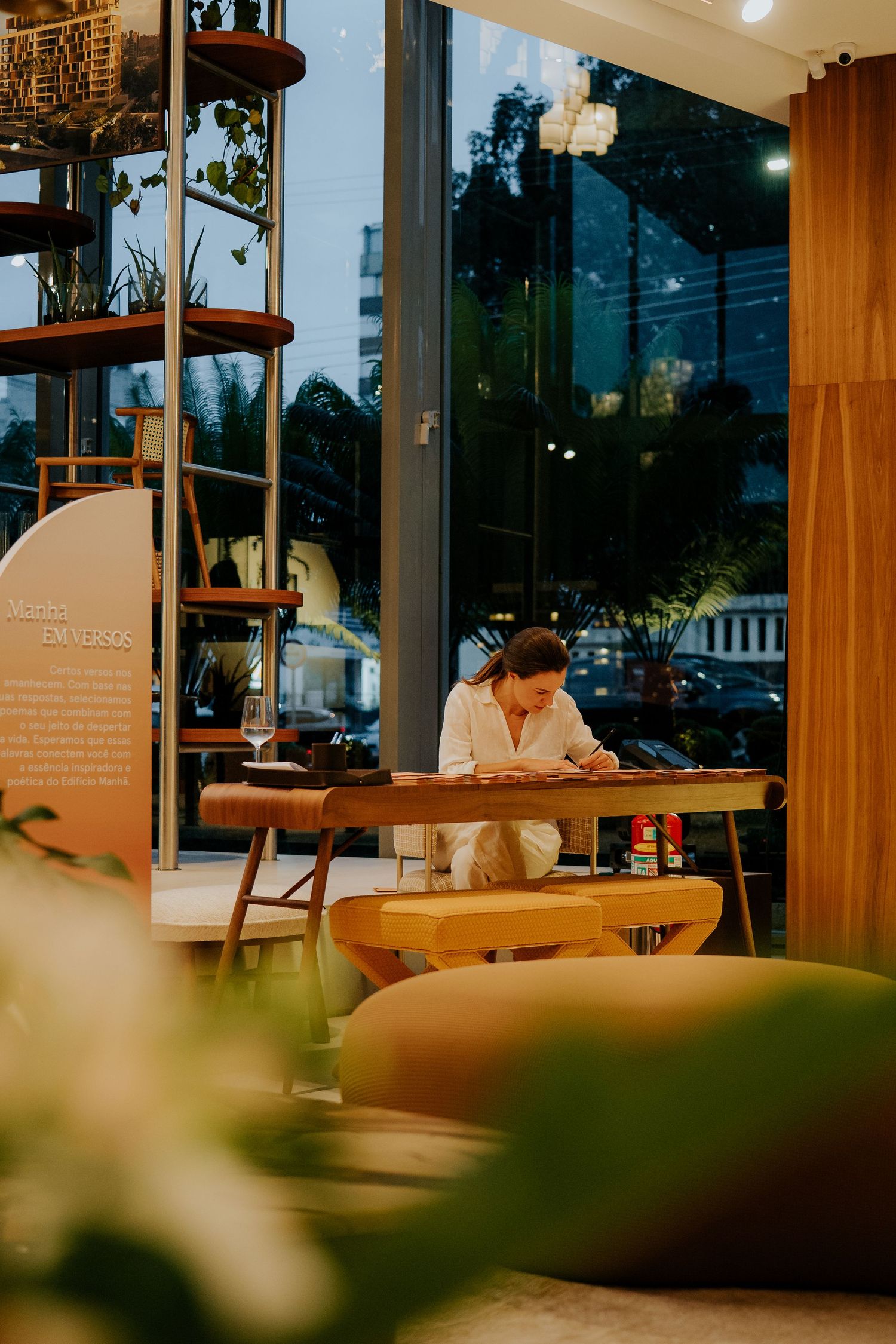 Modern cafe interior with wooden shelves and large windows during evening hours.