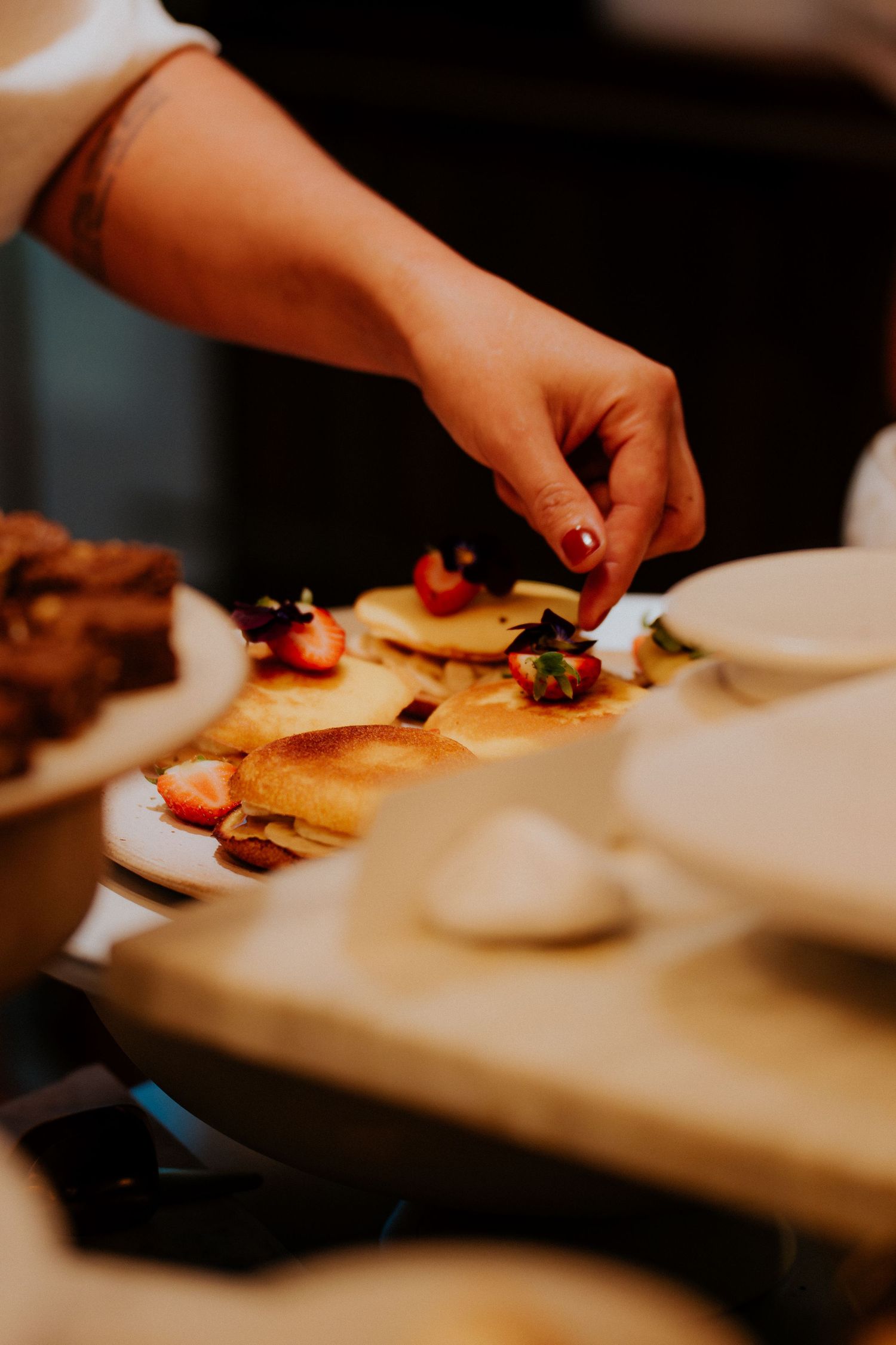 Hand garnishing a dessert plate with berries and decorative elements.
