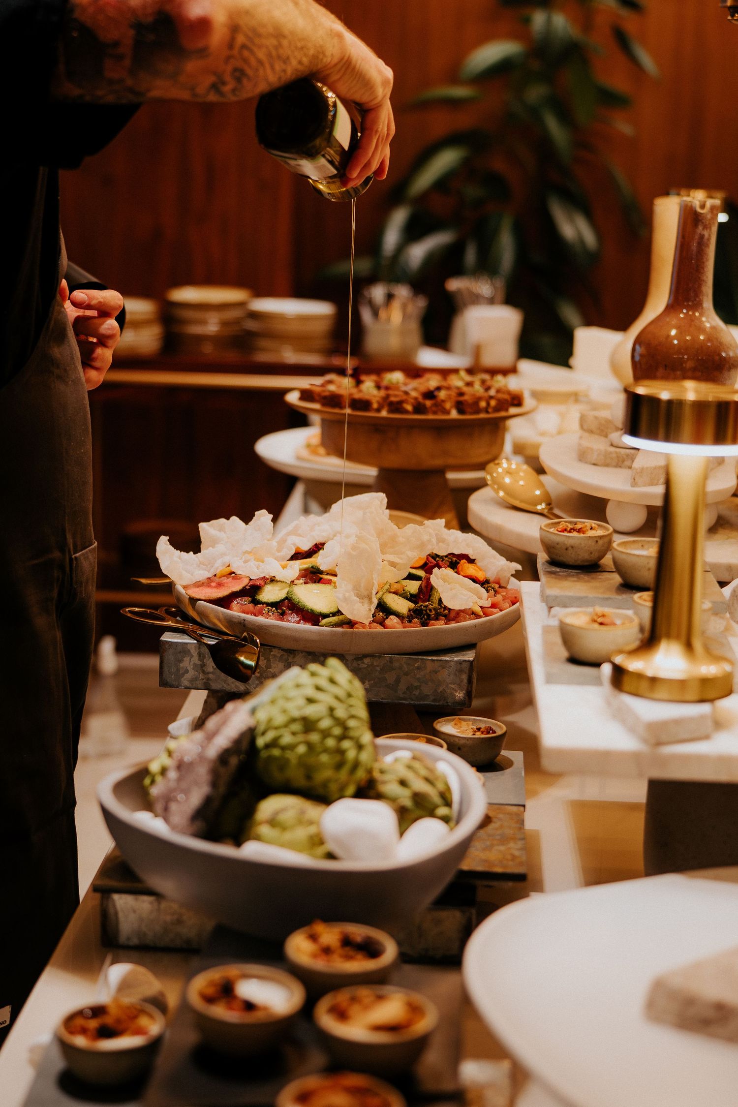 Pouring sauce over gourmet dishes on an elegant buffet display table.