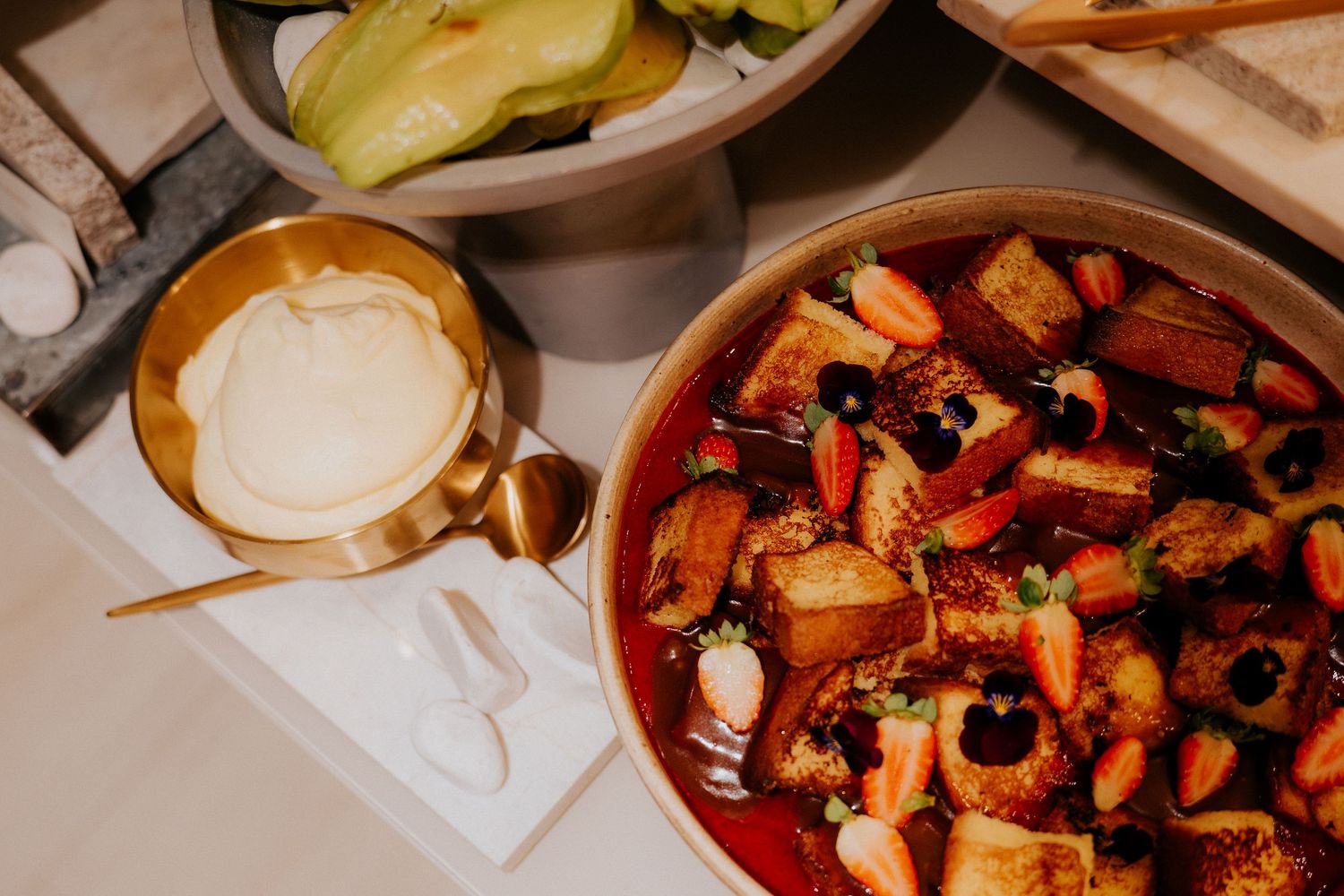 A bowl of colorful roasted vegetables with dip served in a rustic setting.