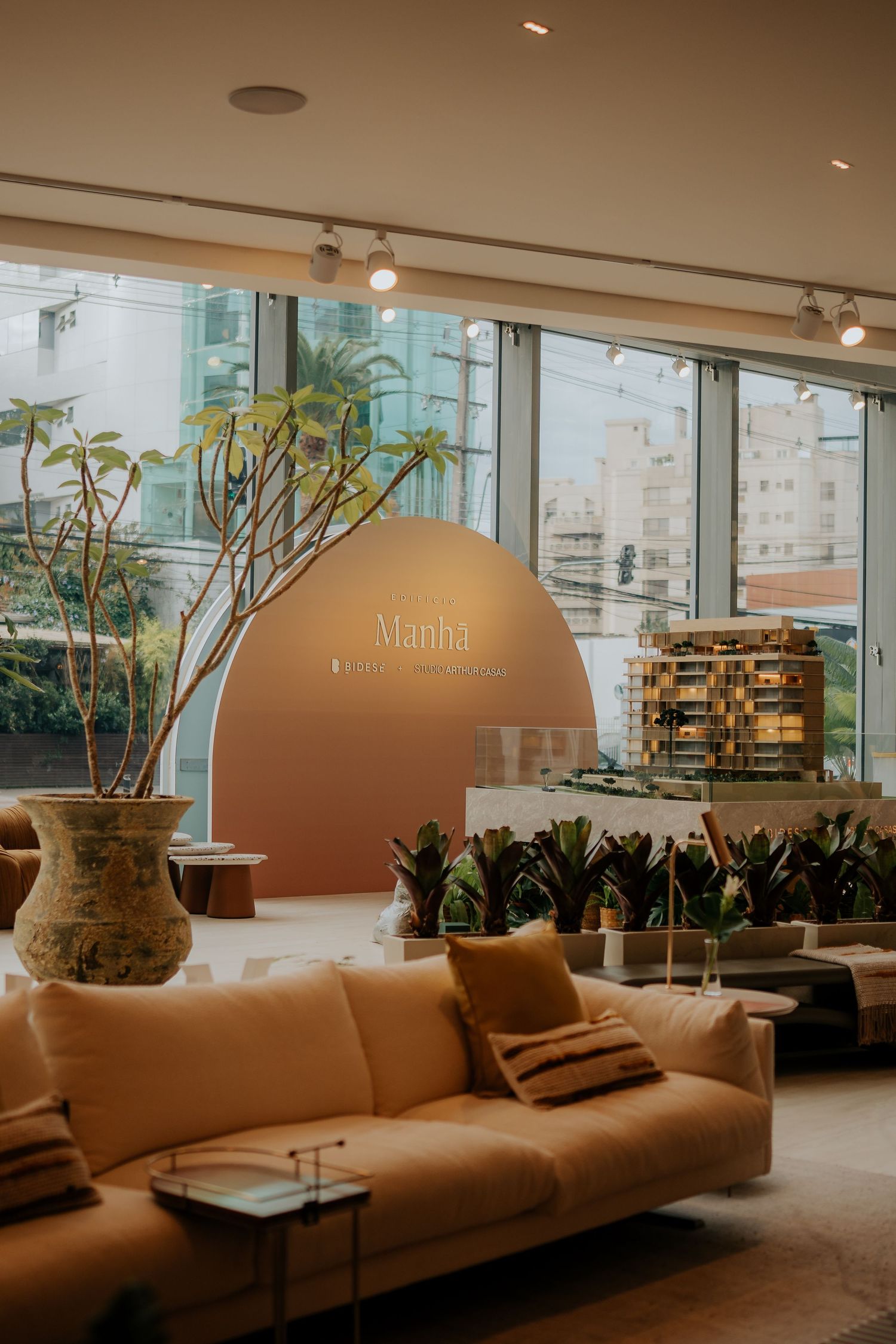 Modern lounge area with beige curved sofa and indoor plants in a contemporary office space.