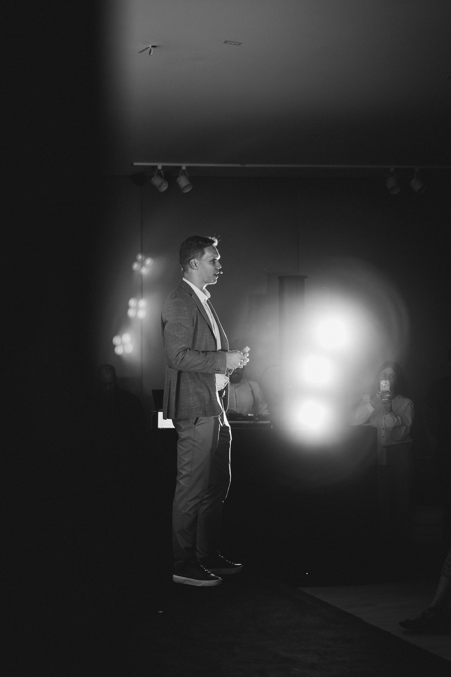 Figure standing in dimly lit room with dramatic spotlight effect.