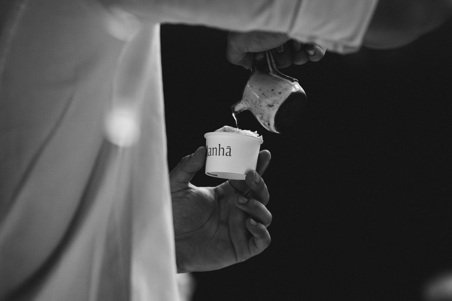 Black and white close-up of hand holding branded merchandise.