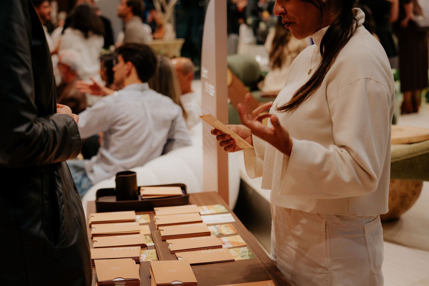 Staff member in white uniform handling products at retail counter display.