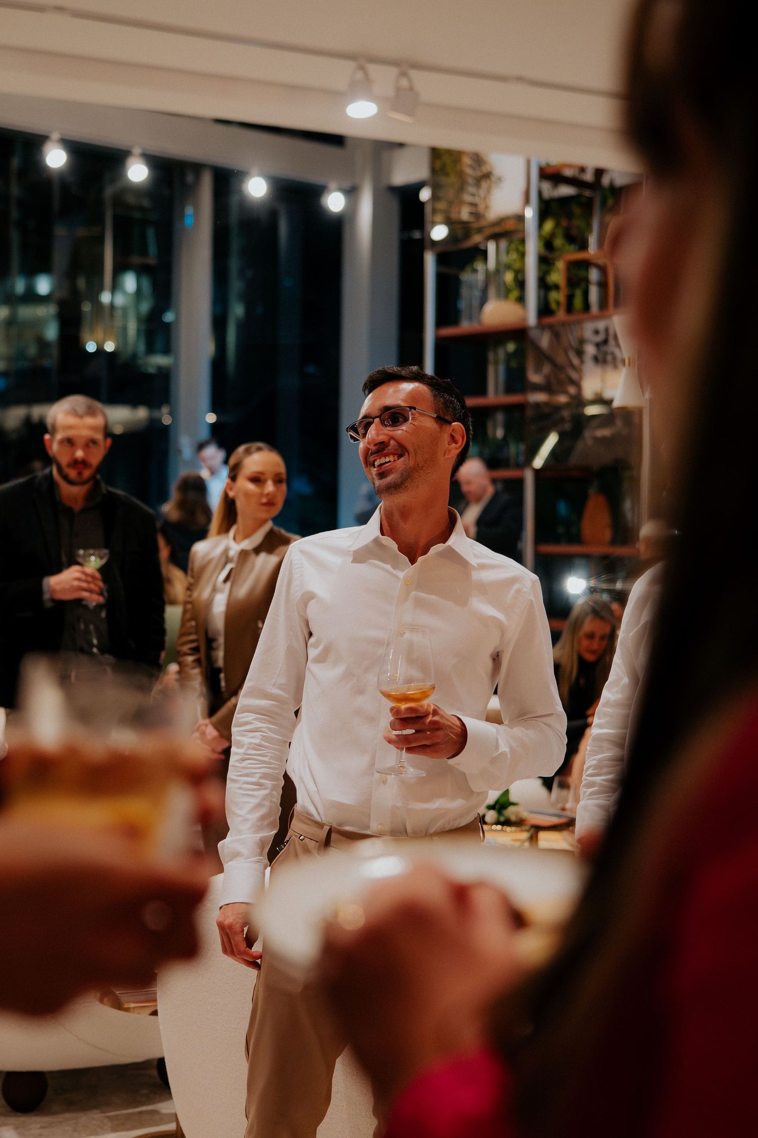 People socializing at evening business event with wine glasses.