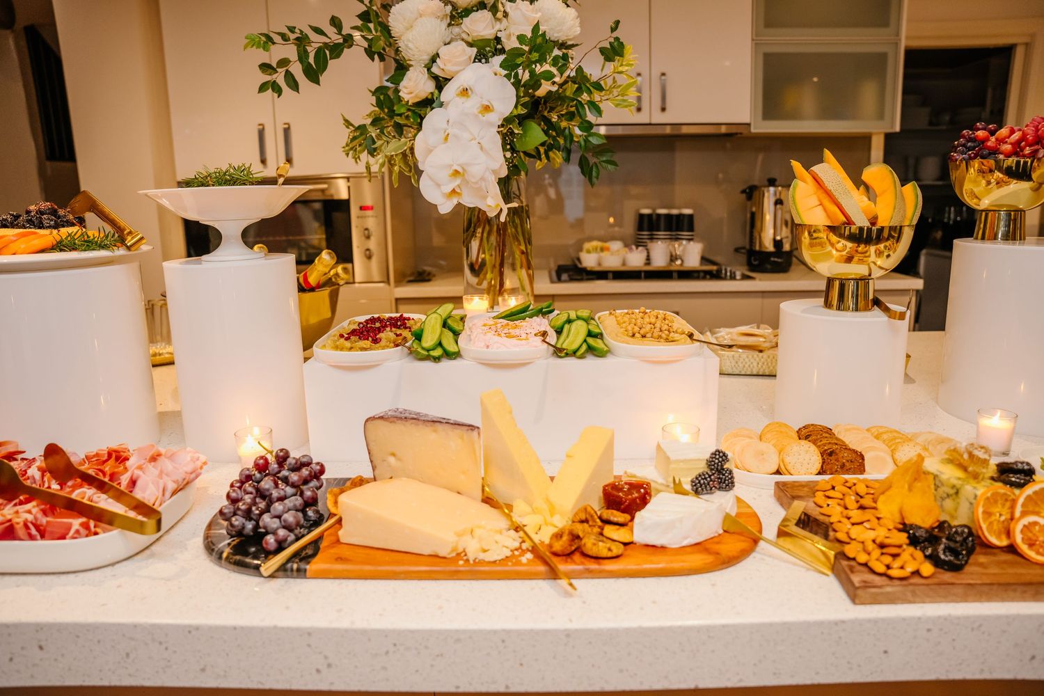 Gourmet cheese board with assorted cheeses, fruits, nuts, and honey arranged on wooden cutting boards.
