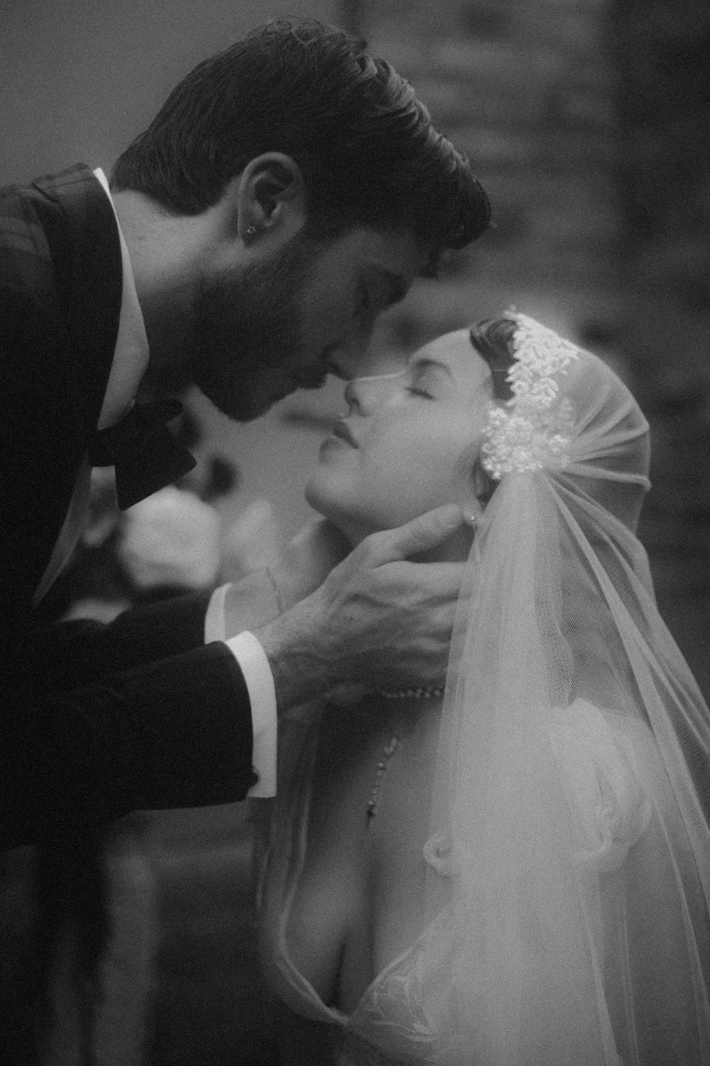 A black and white sequence of romantic wedding kiss photos showing a tender moment between newlyweds with flowing veil.