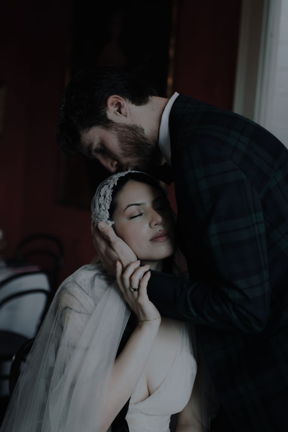 Tender wedding moment in dramatic lighting with vintage-inspired styling.
