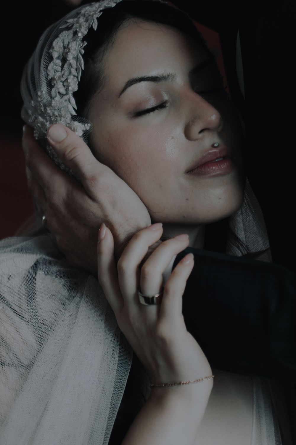 Dreamy bridal portrait with lace veil detail in soft, moody lighting.