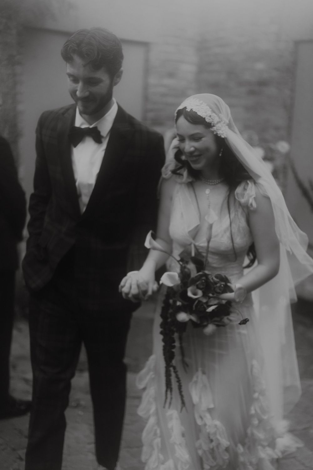 A black and white wedding photograph capturing a joyful moment between the wedding party.