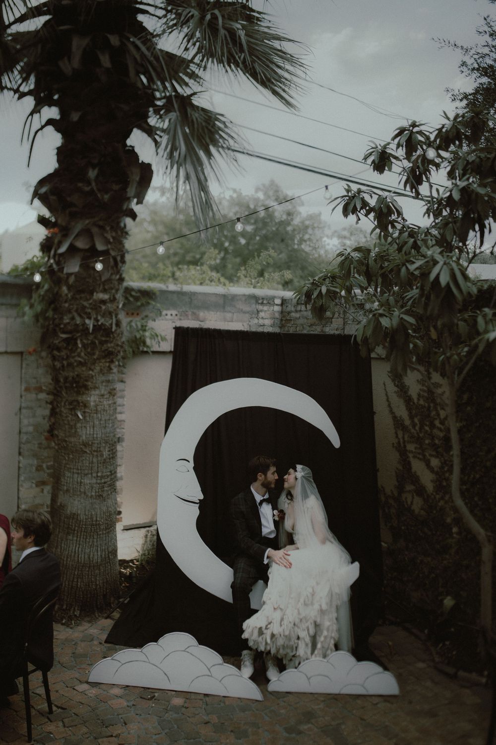 Wedding photo session in front of a large white backdrop with palm trees in the background.