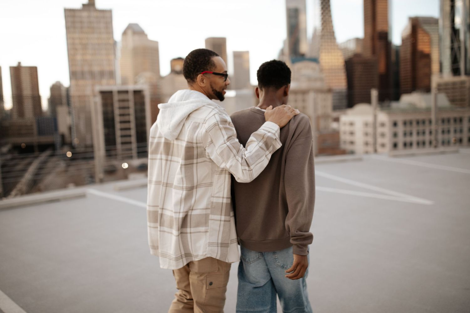 Group sharing joyful moments together on a rooftop with city skyline backdrop in warm sunlight.