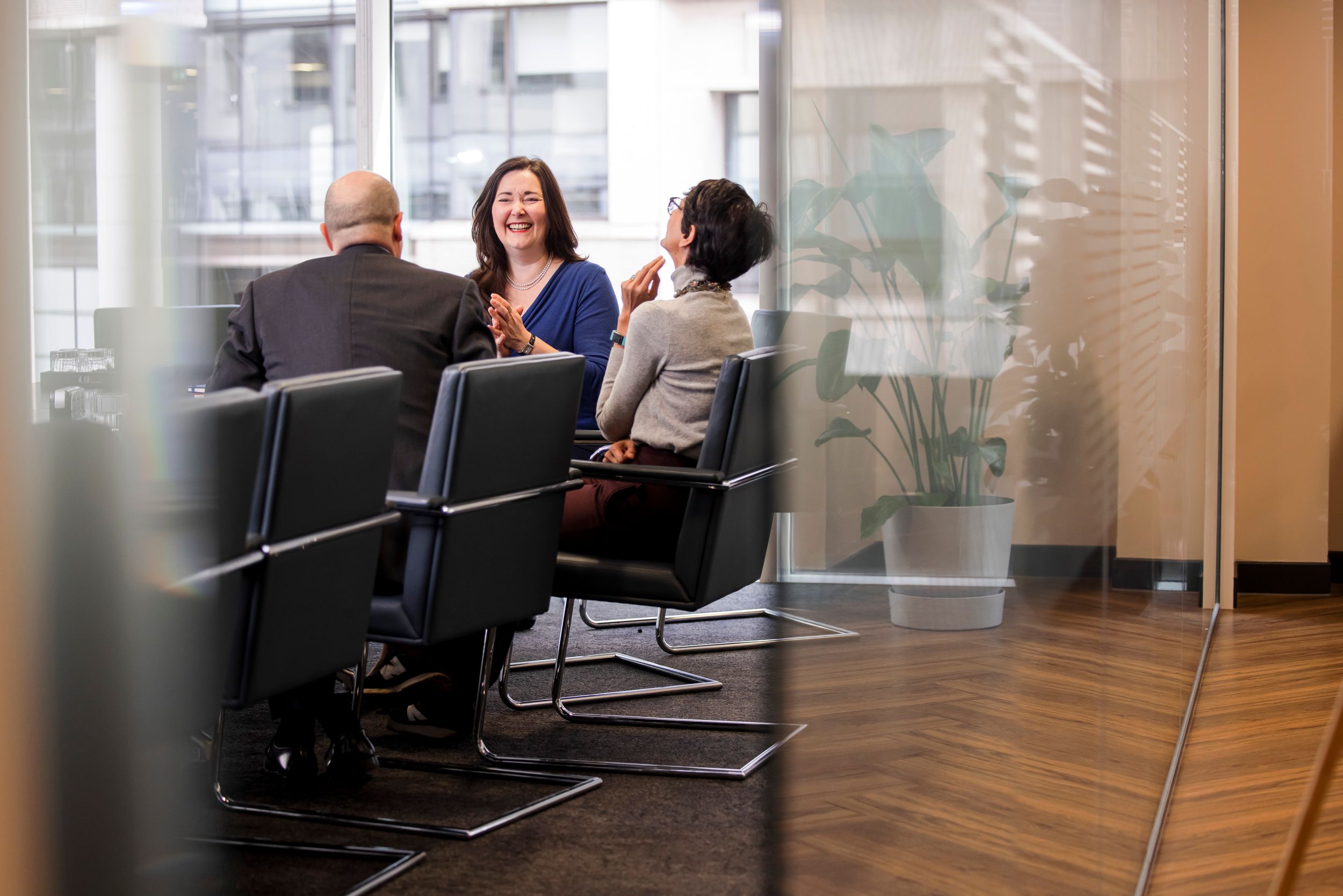Modern office meeting room with glass walls and business professionals having discussion.