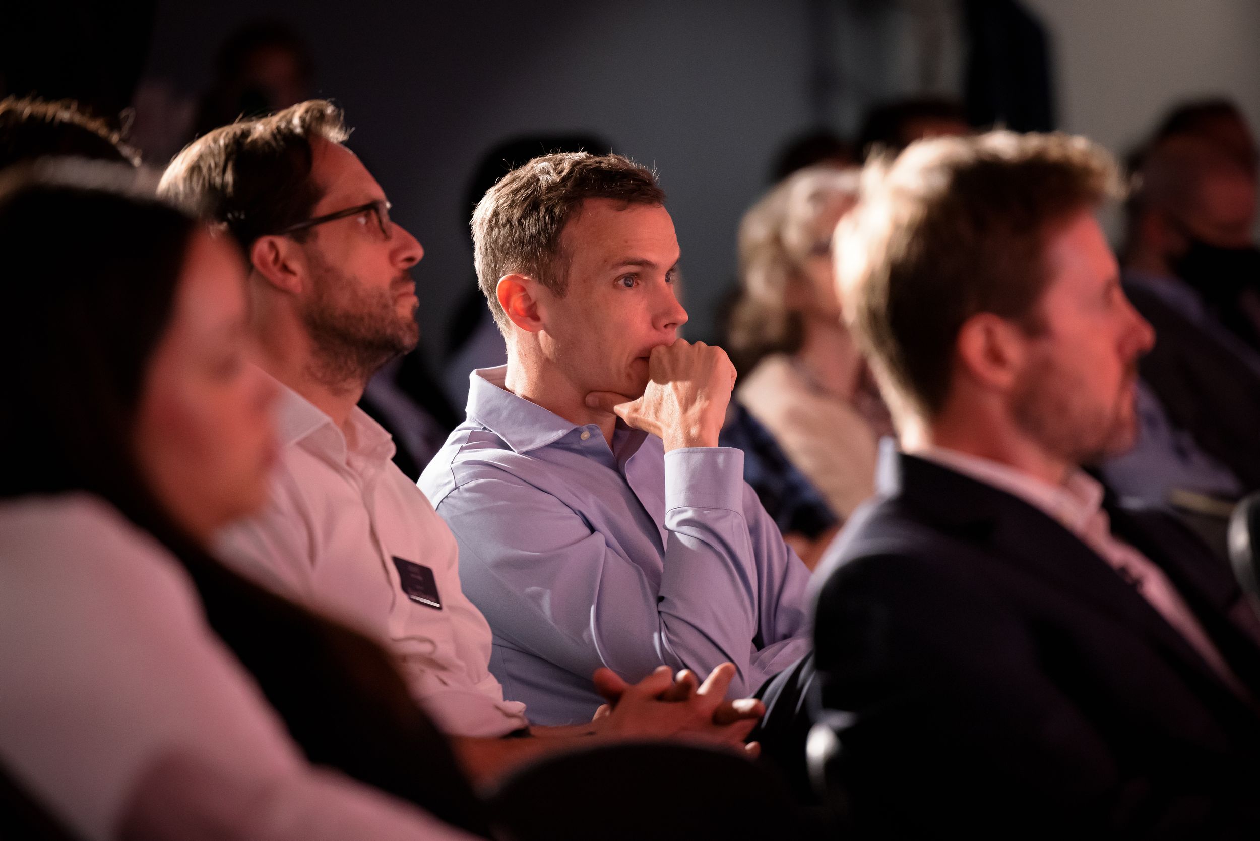 Side view of audience members watching intently during a conference presentation.