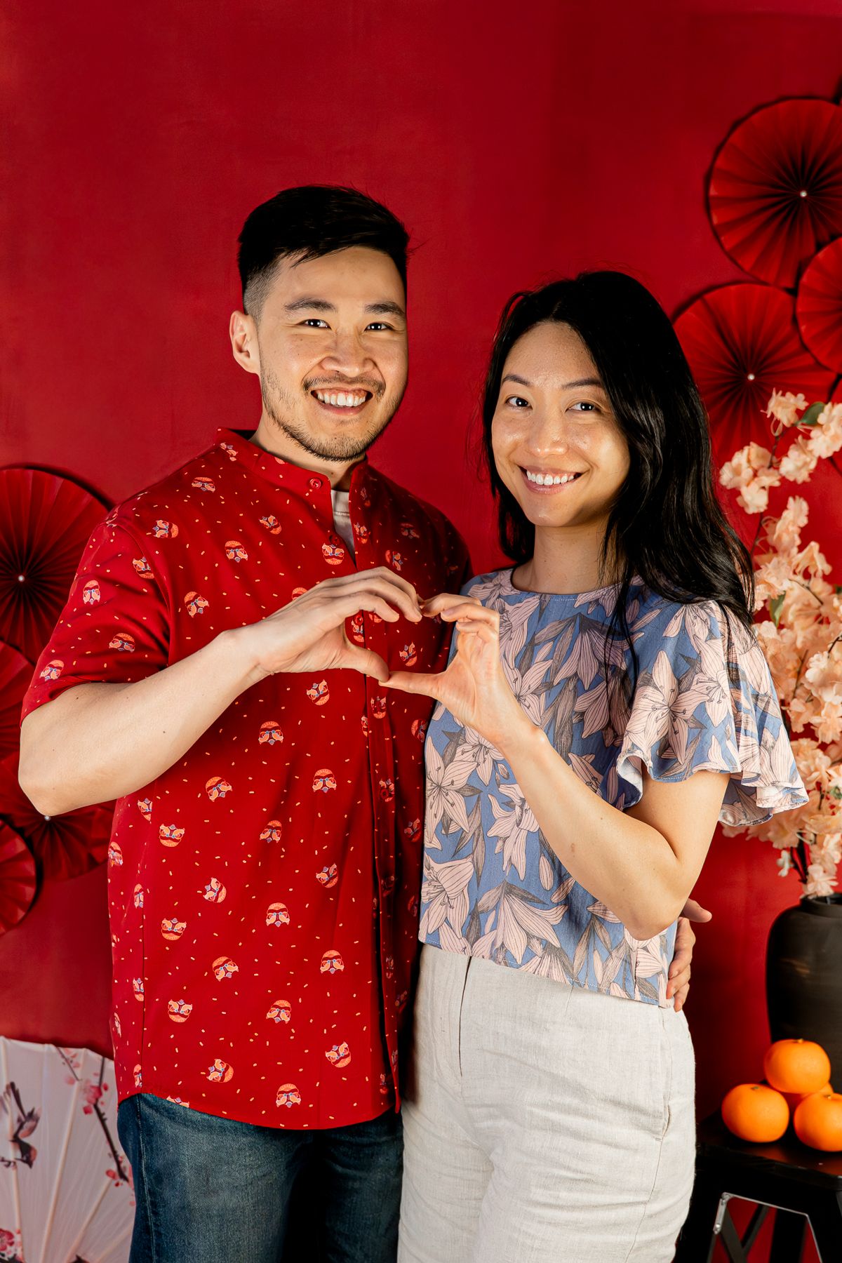 A couple in red and blue outfits poses together against a Chinese New Year backdrop during a Melbourne Chinese New Year Photoshoot.