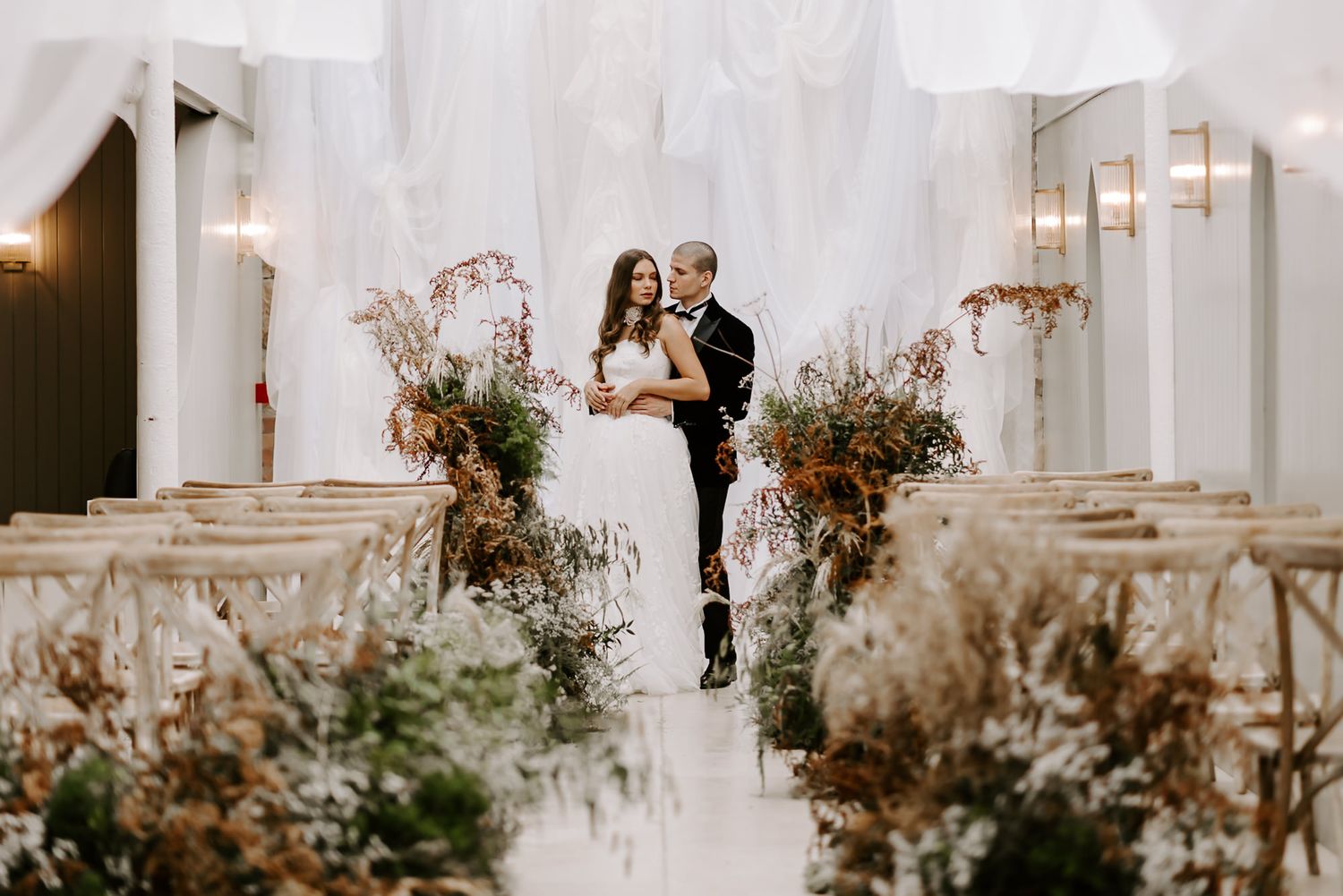 Elegant wedding venue decorated with dried floral arrangements and white draping creates a romantic atmosphere.