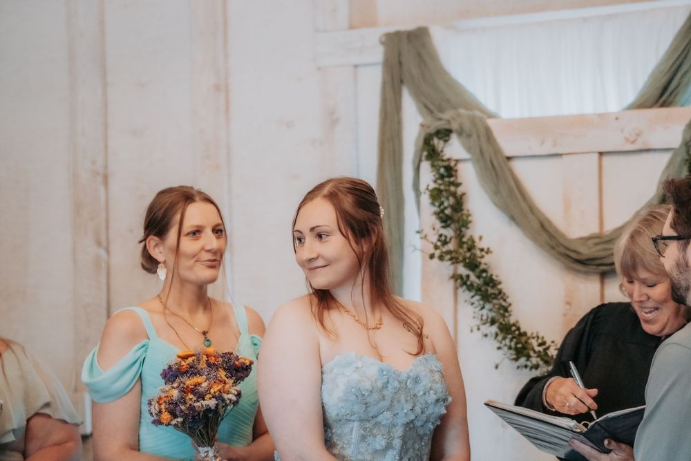 Two people share an intimate moment during a wedding celebration with floral decor and natural lighting.
