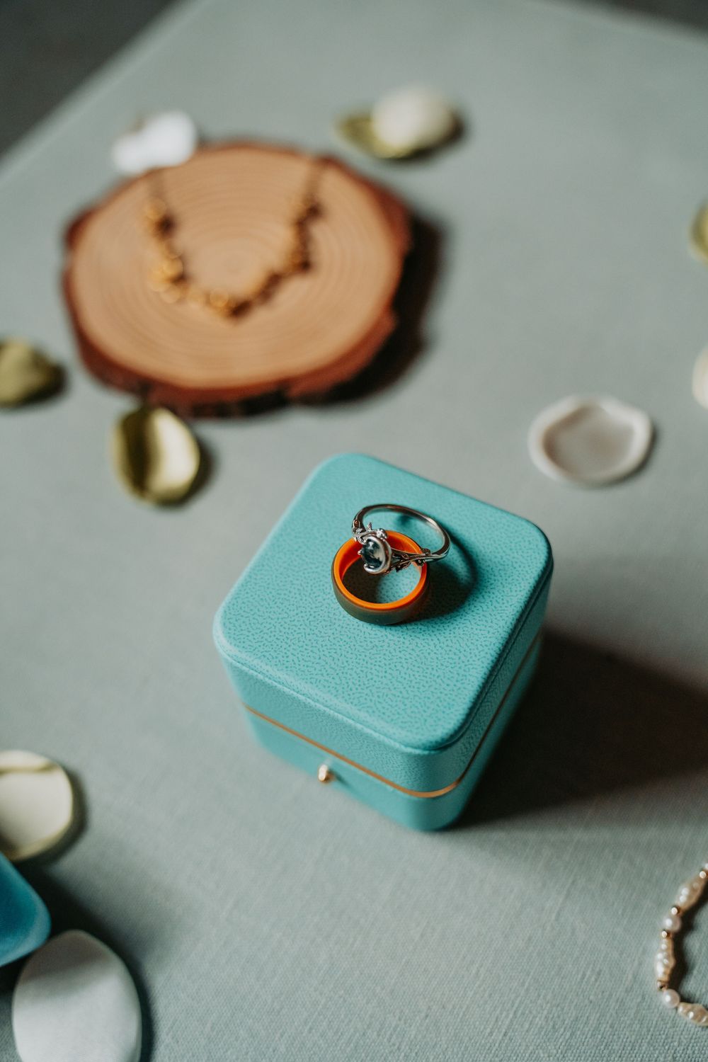 Turquoise engagement ring box with wooden accent displayed on light gray fabric surface.