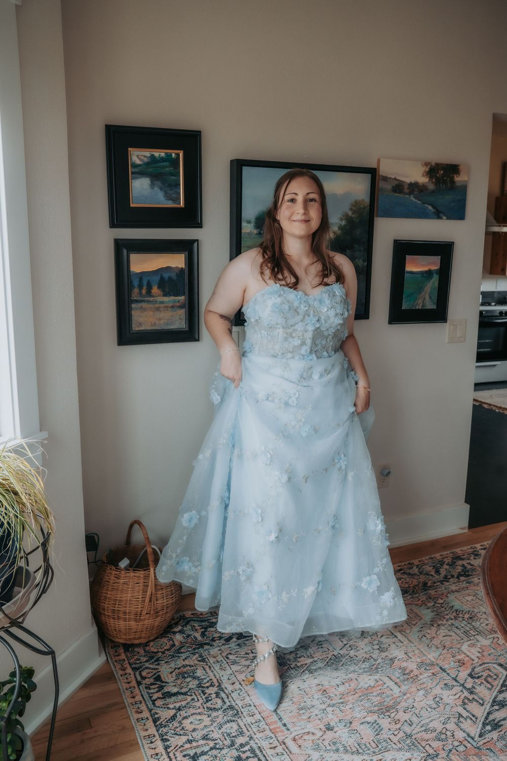 A light blue formal dress with floral details is shown in multiple angles on a patterned rug in an interior setting.