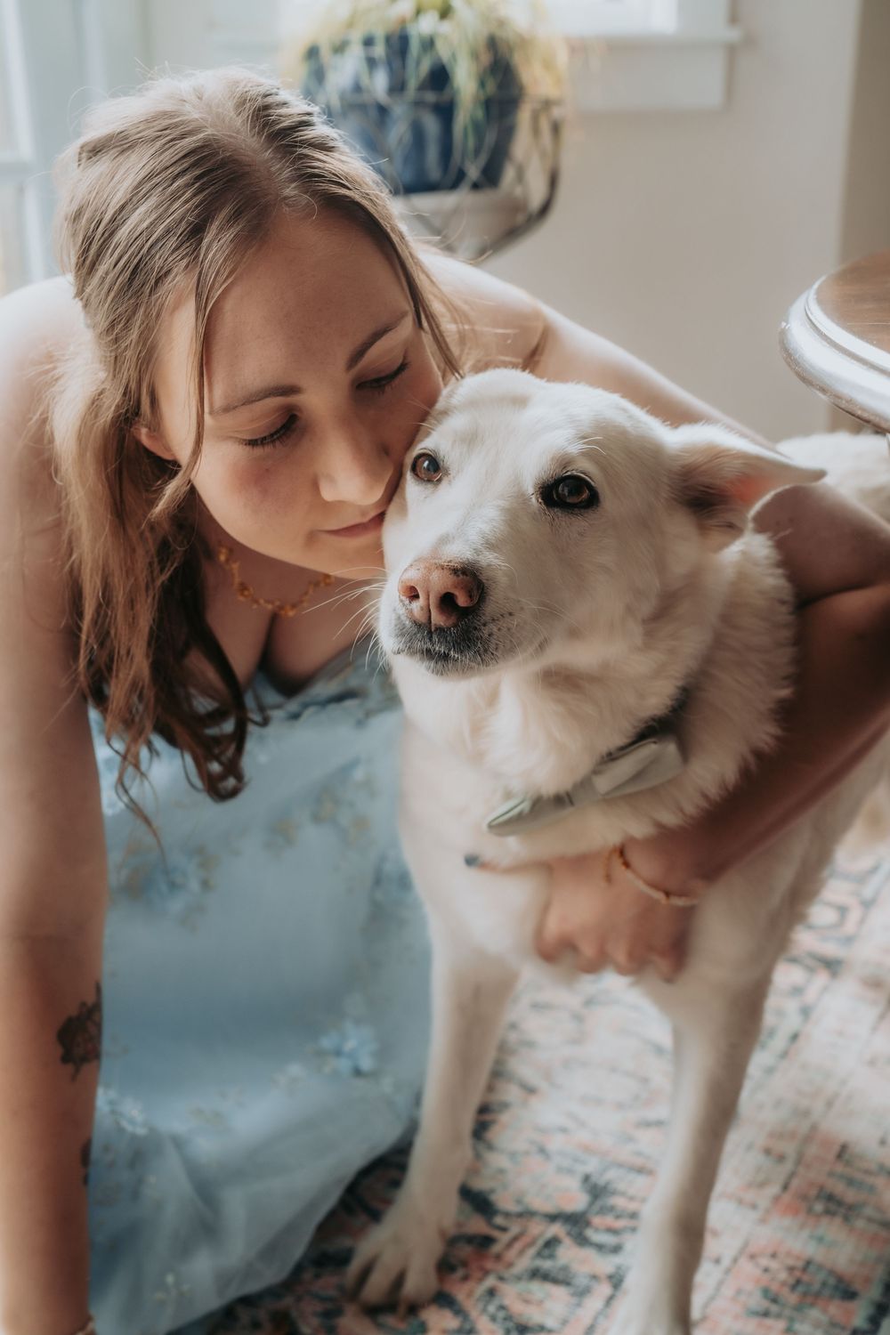 Sweet moment between a white dog and owner in casual indoor setting with natural lighting.