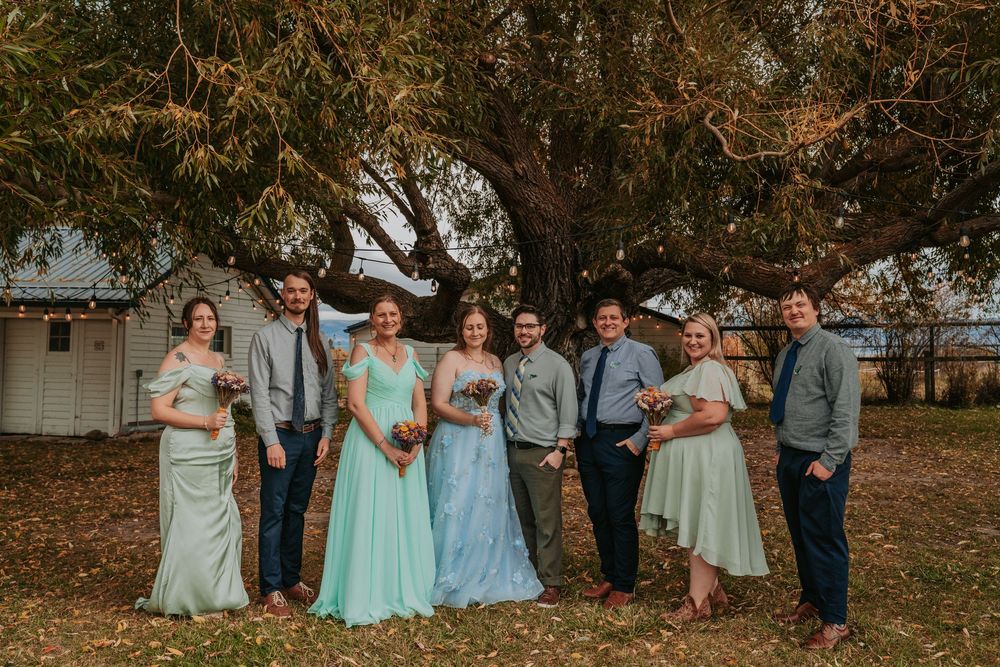 Wedding party gathered outdoors in autumn setting wearing coordinated mint and blue attire.