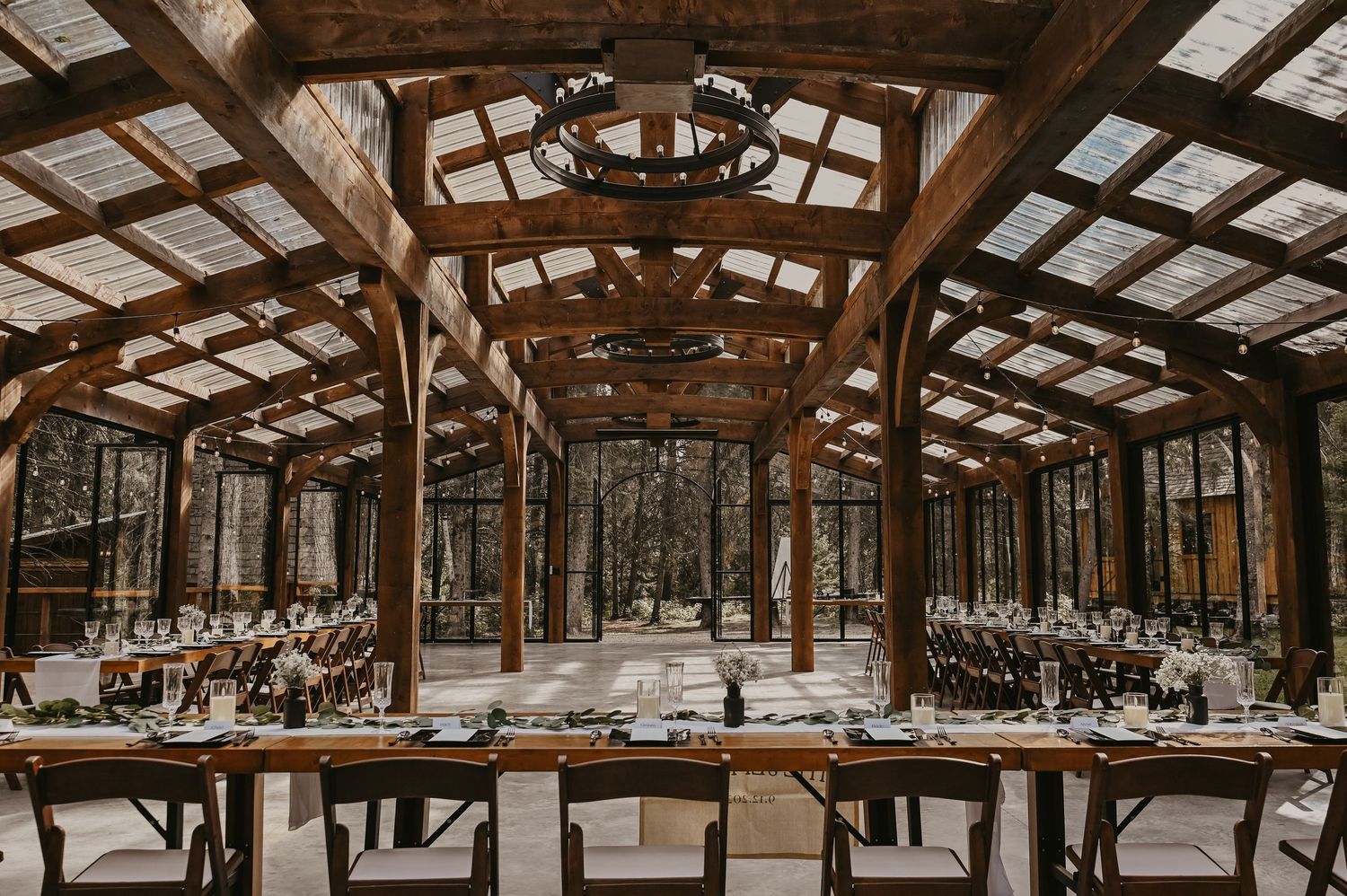 Panoramic view of rustic wooden barn interior with exposed beams and string lights.