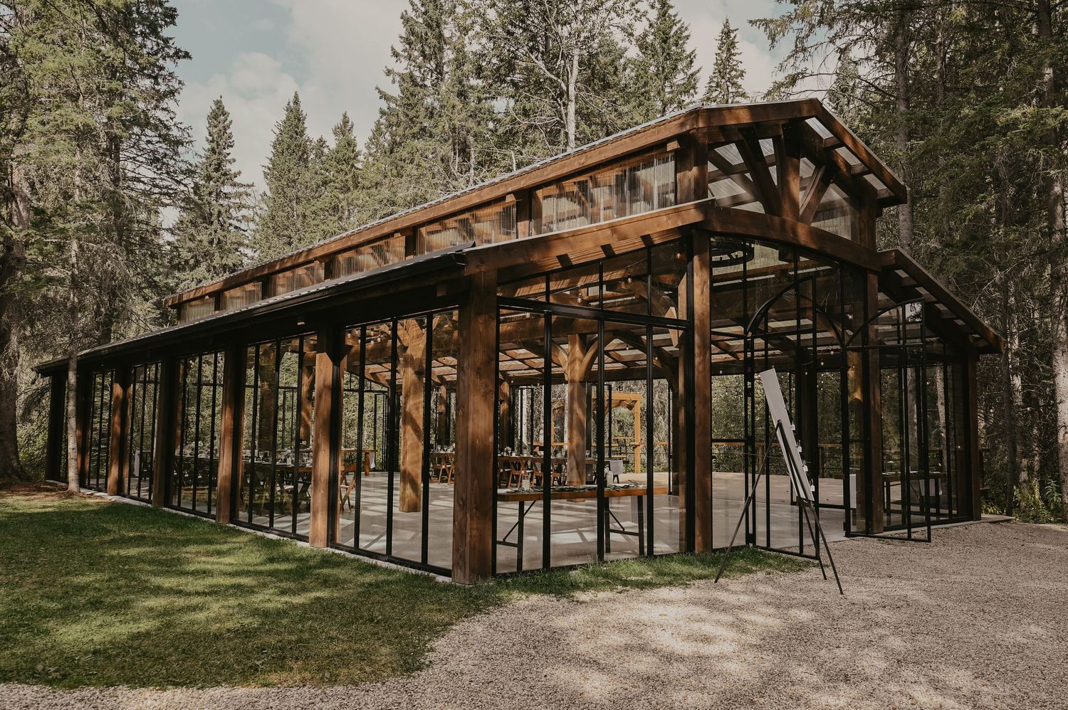Scenic outdoor wedding venue with wooden pavilion surrounded by tall pine trees.