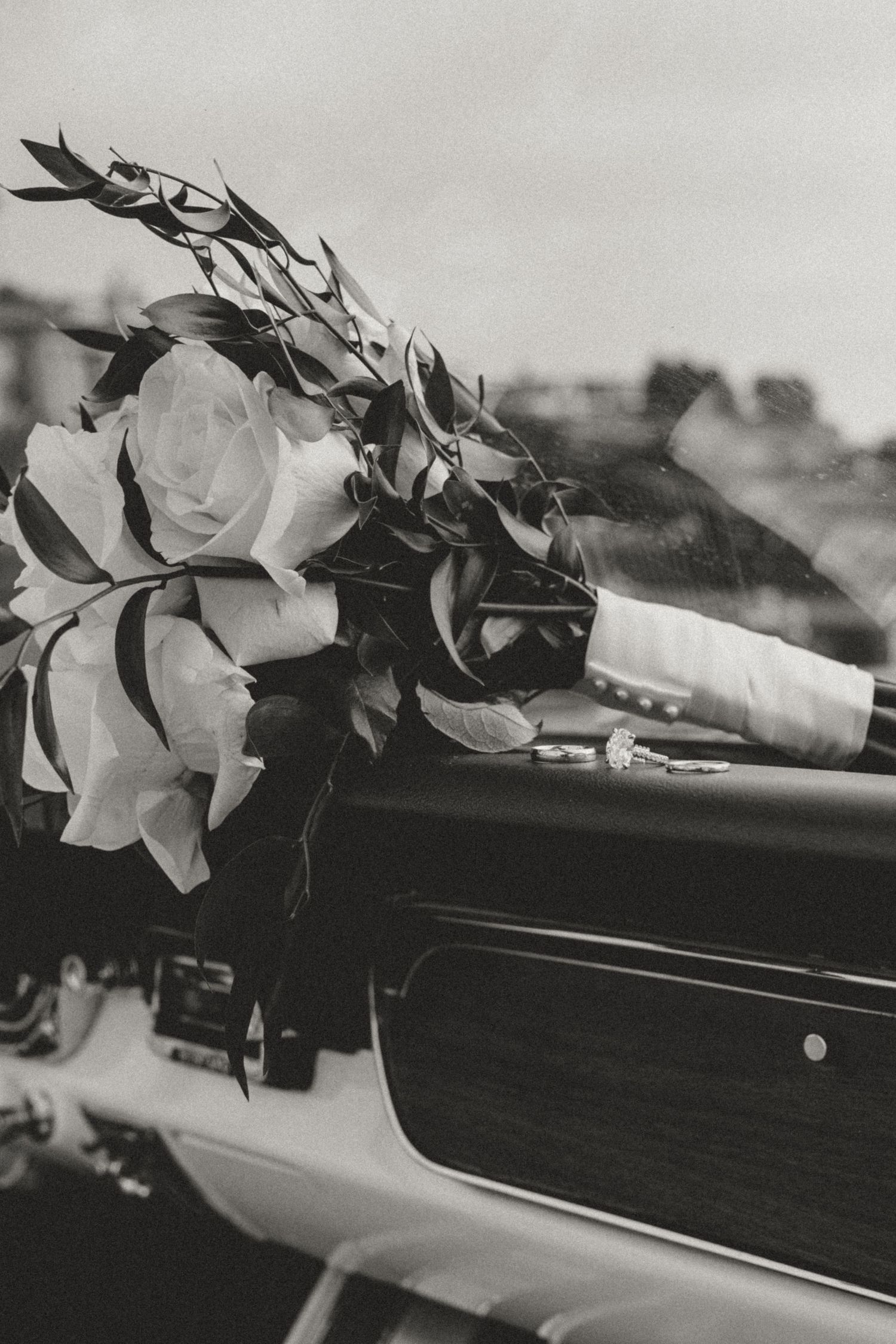 Black and white wedding ceremony photos of couple kissing under floral arch.