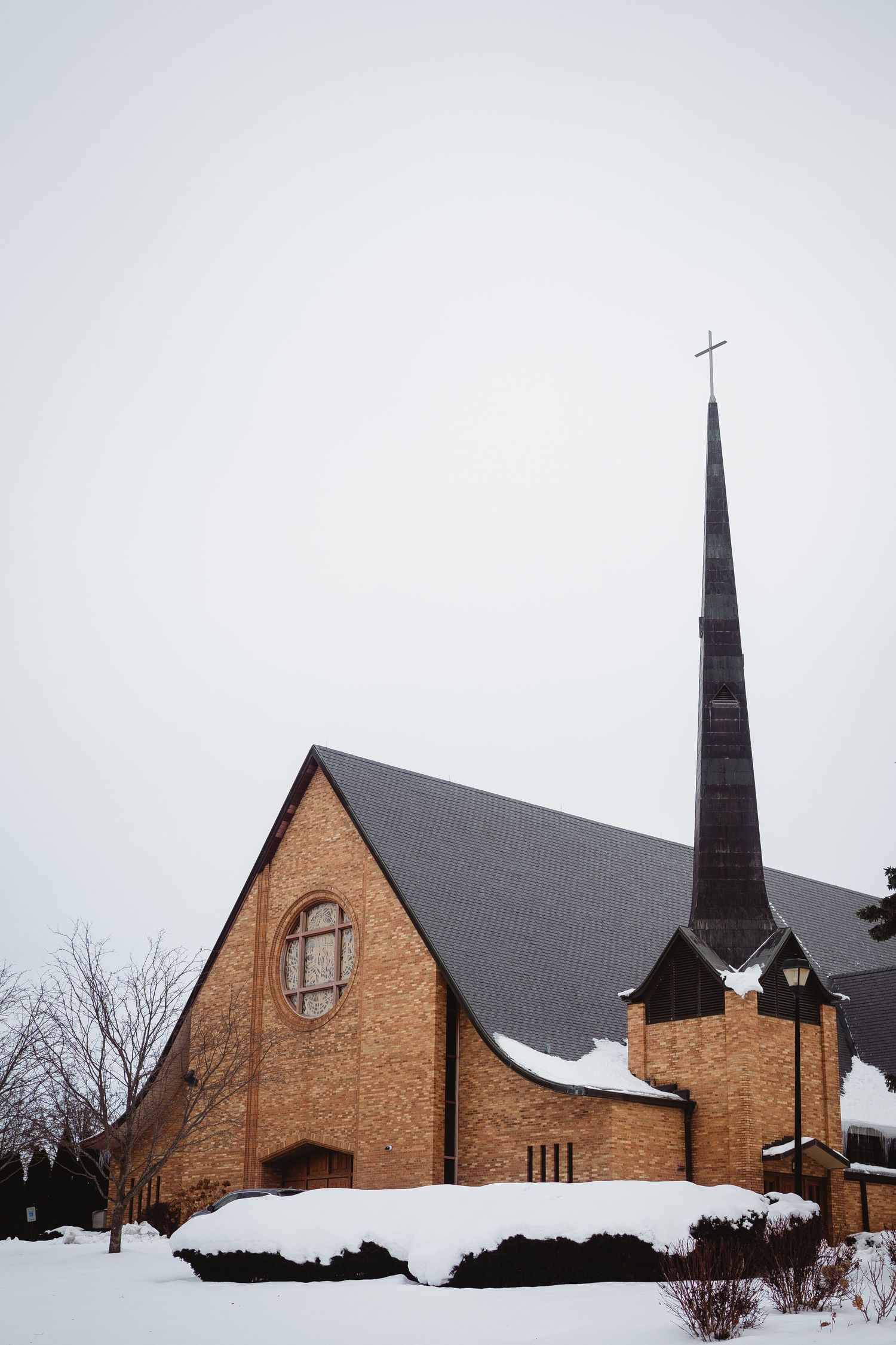 Snow-covered brick church with tall spire and peaked roof shown in a series of three winter views.