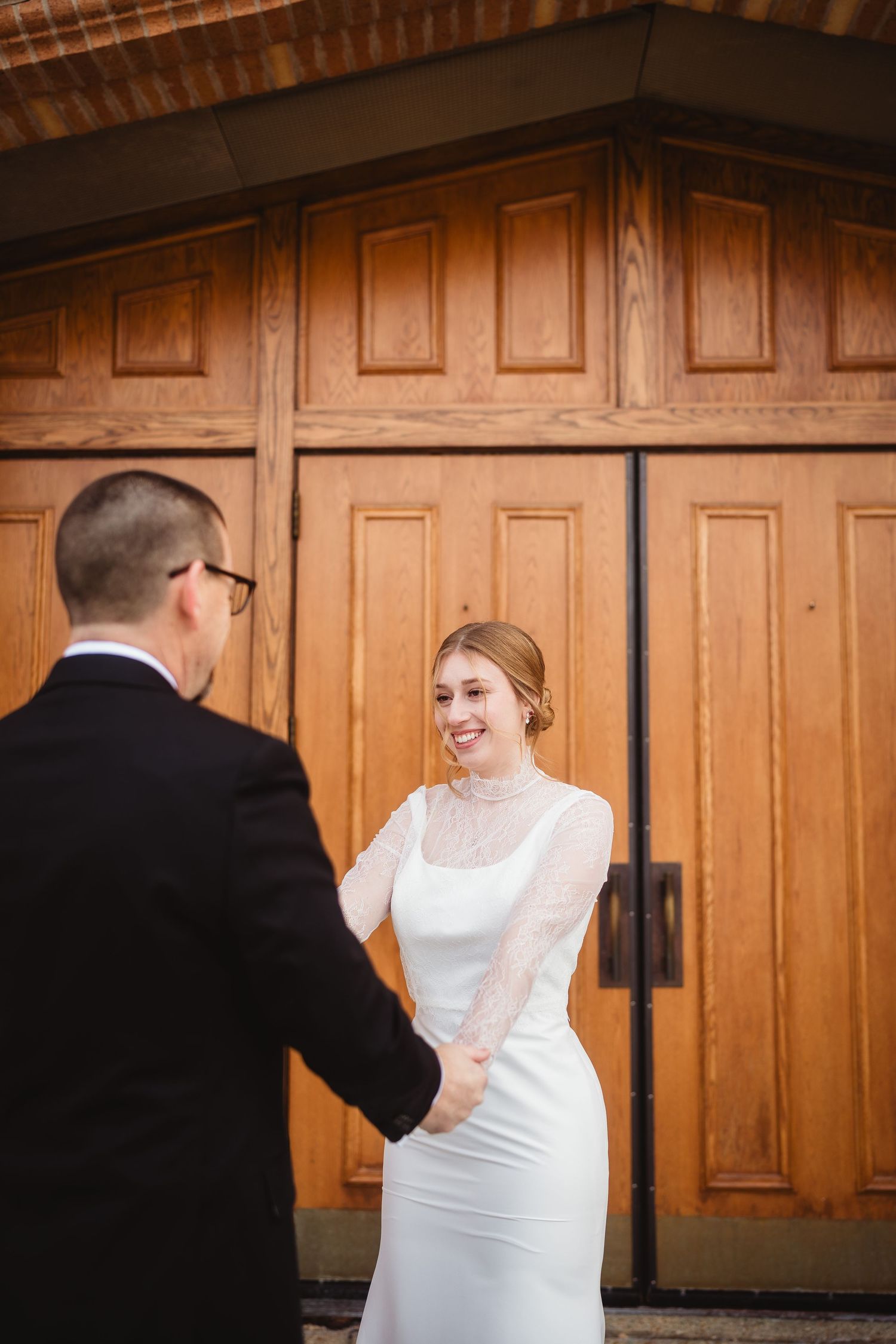 A couple shares a tender moment in front of wooden doors during their winter wedding celebration.