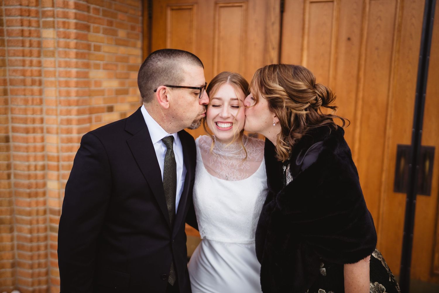 Group of people sharing joyful moments in front of wooden church doors.