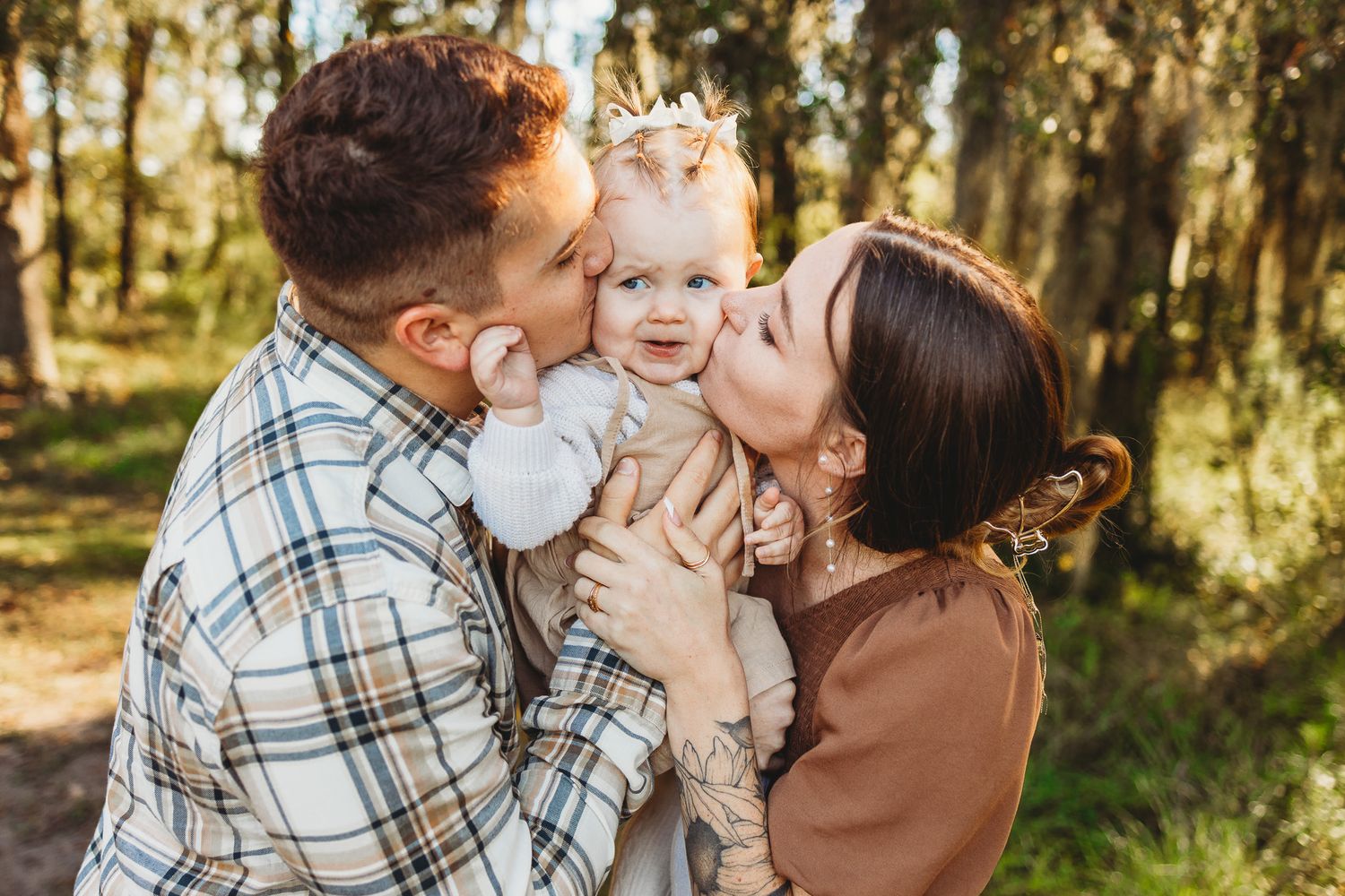 A sweet family moment captured in golden sunlight amongst trees during a photo session.