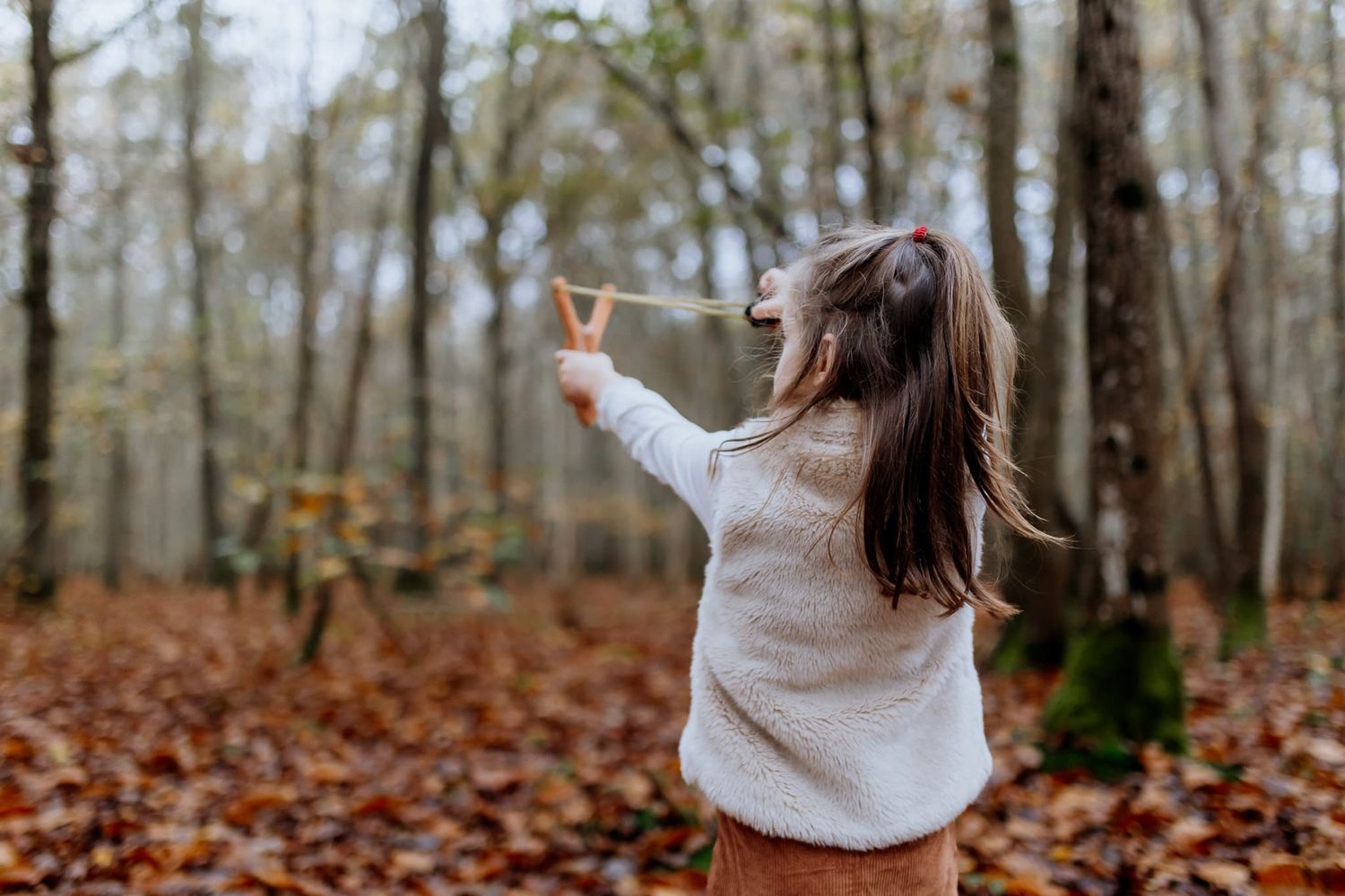 Petite fille qui joue au lance-pierre dans la forêt
