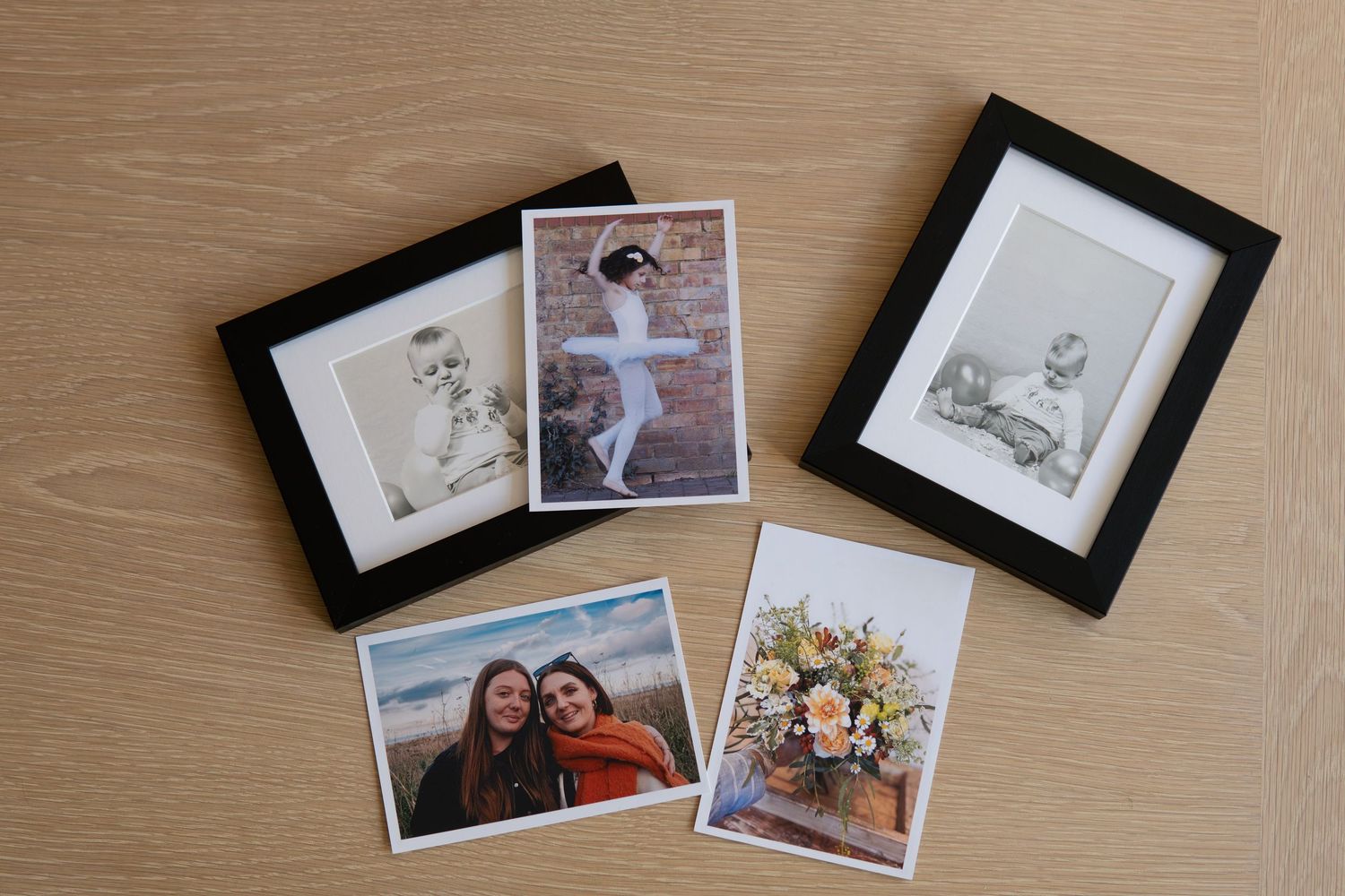 Still-life photograph of photographs, arranged on a wooden table and photographed in natural window light