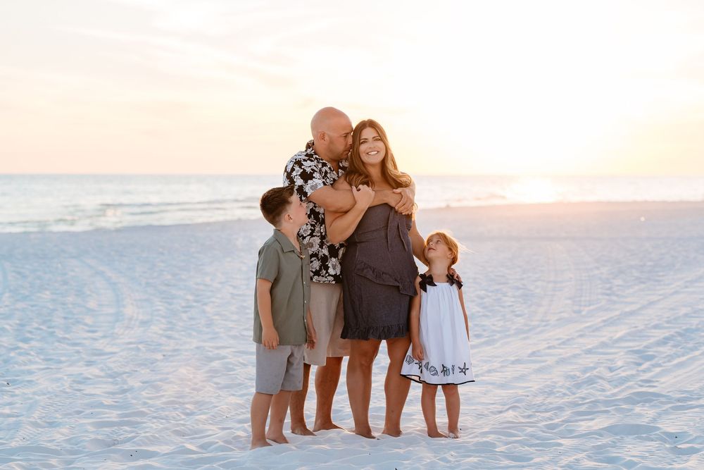 A group of people enjoying a sunset photo session on a pristine white sand beach.