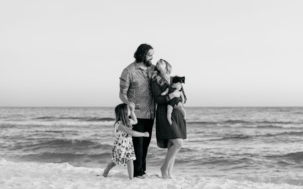 People enjoying a day at the beach in black and white, walking near the ocean waves.