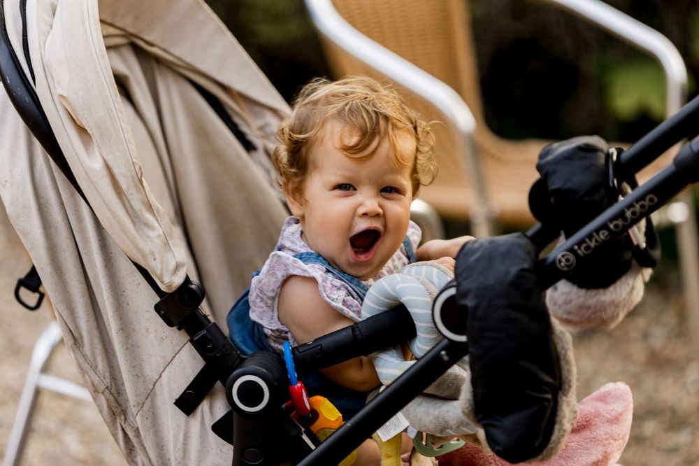 Children laugh and play in strollers during an outdoor event.