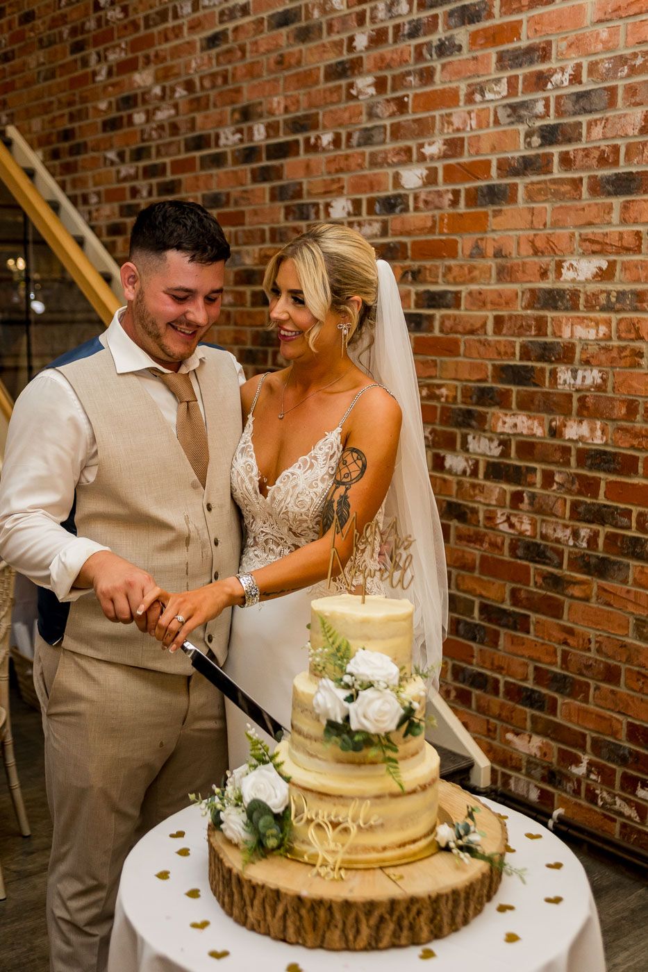Couple shares a playful moment while cutting their wedding cake at rustic venue.